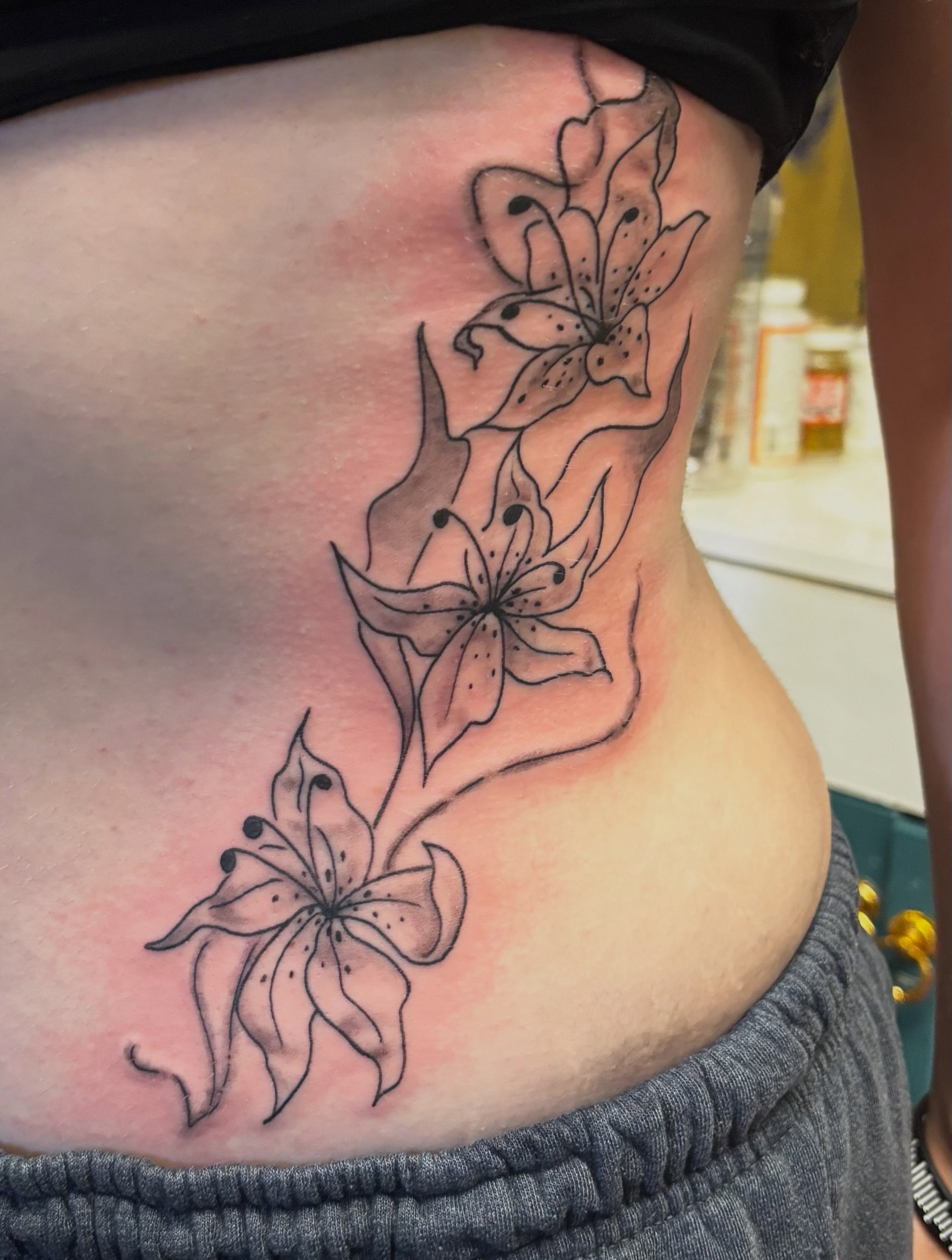 Lilies black and grey tattoo on the ribs by Jeff Zuptich