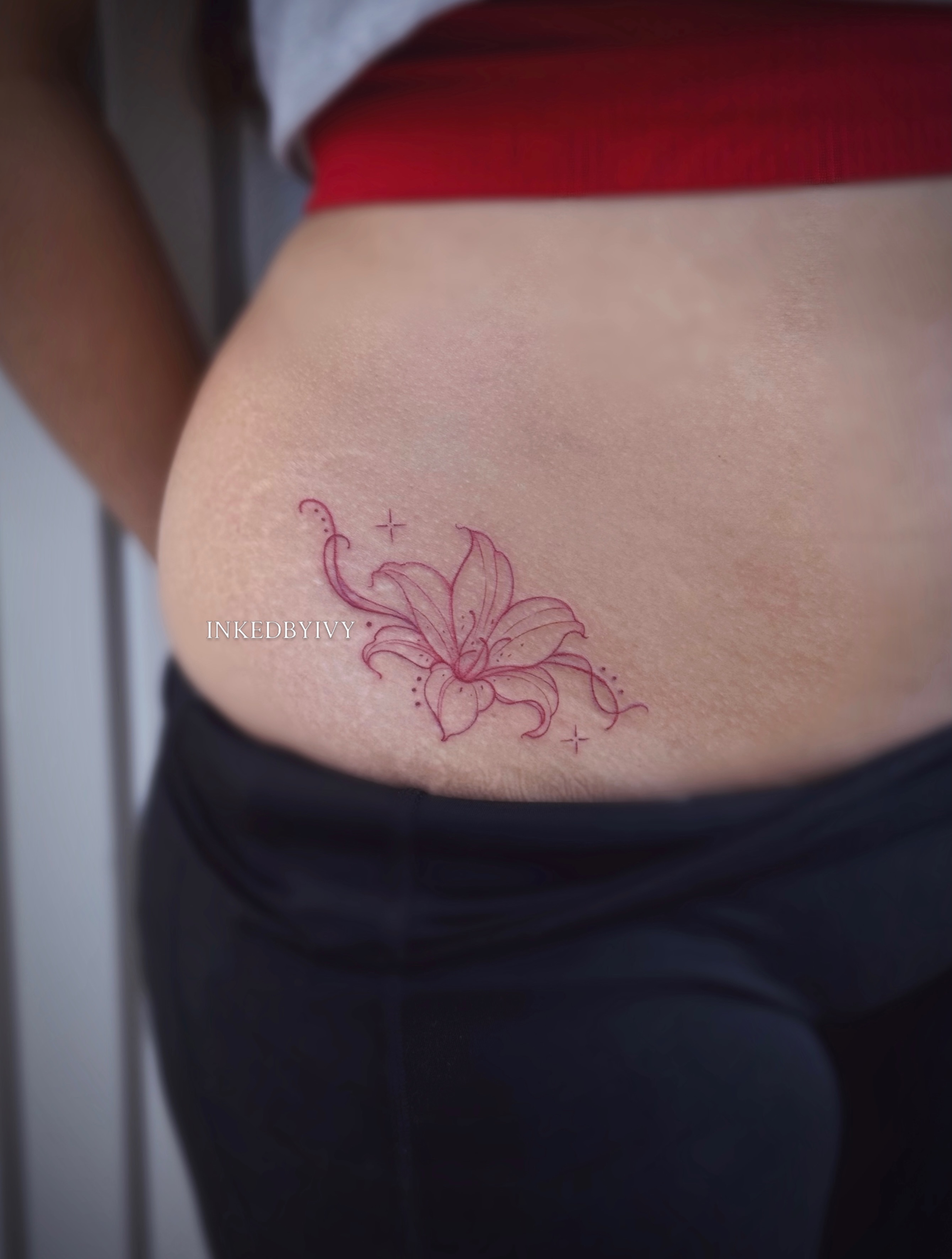 Lily fine line tattoo on the thigh by IVY