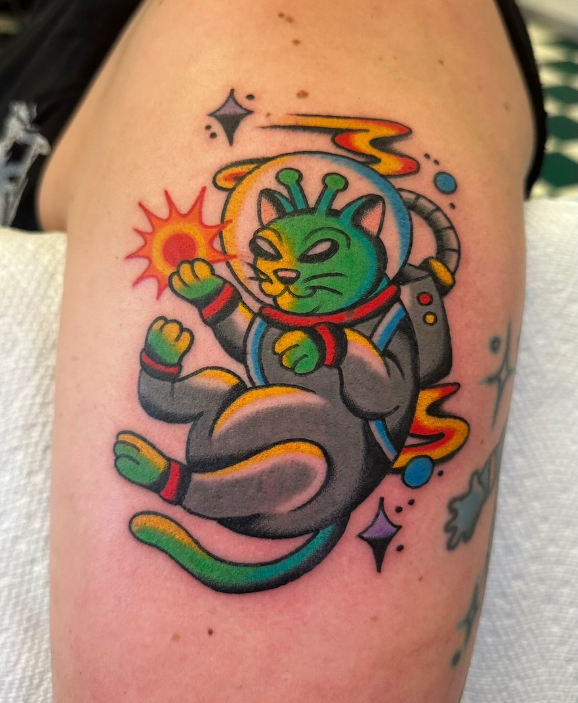 Space cat new school tattoo on the upper arm by Zahra Niedermann