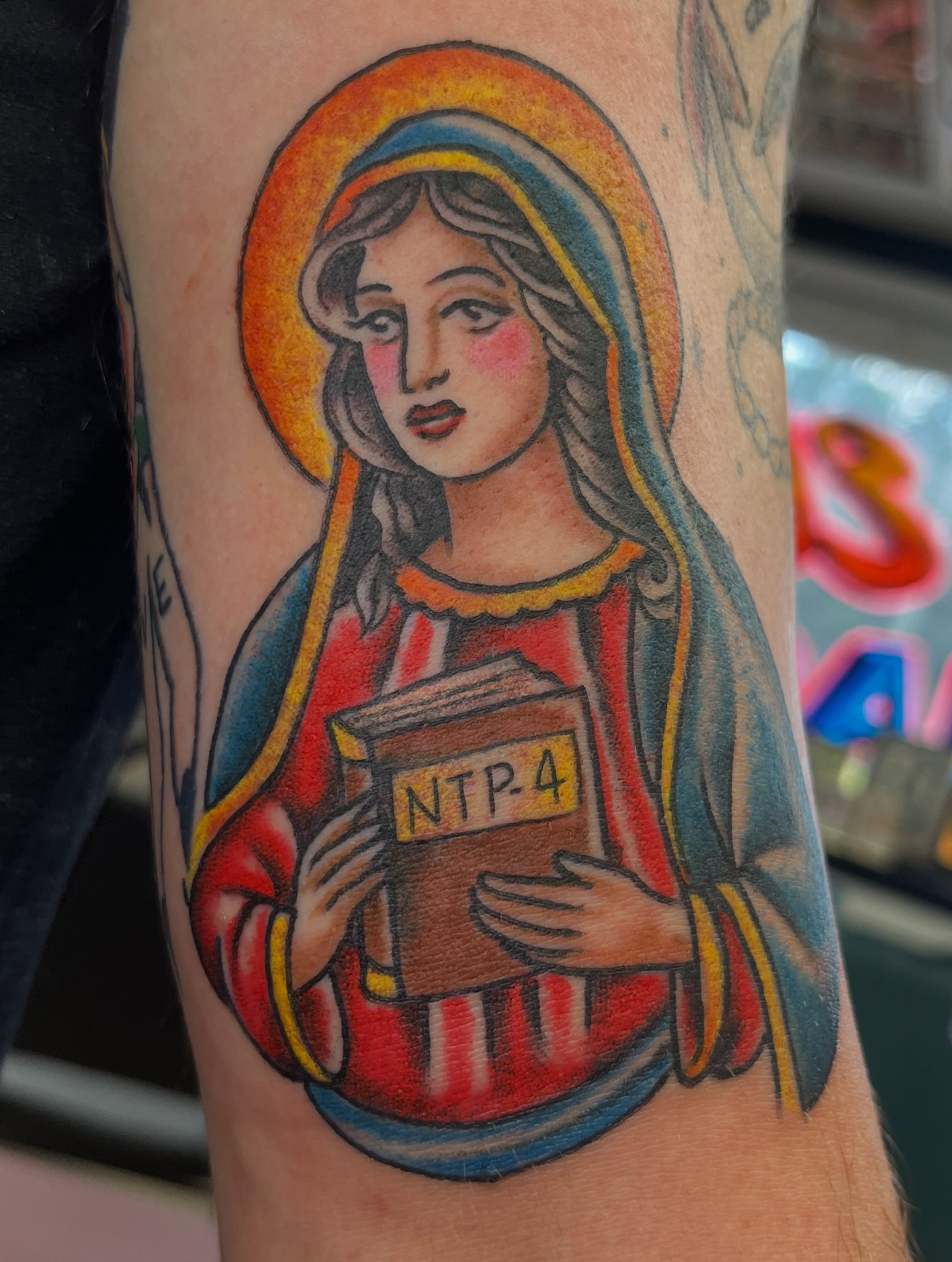 Religious figure holding book American traditional tattoo on the forearm by Steve Tiberi