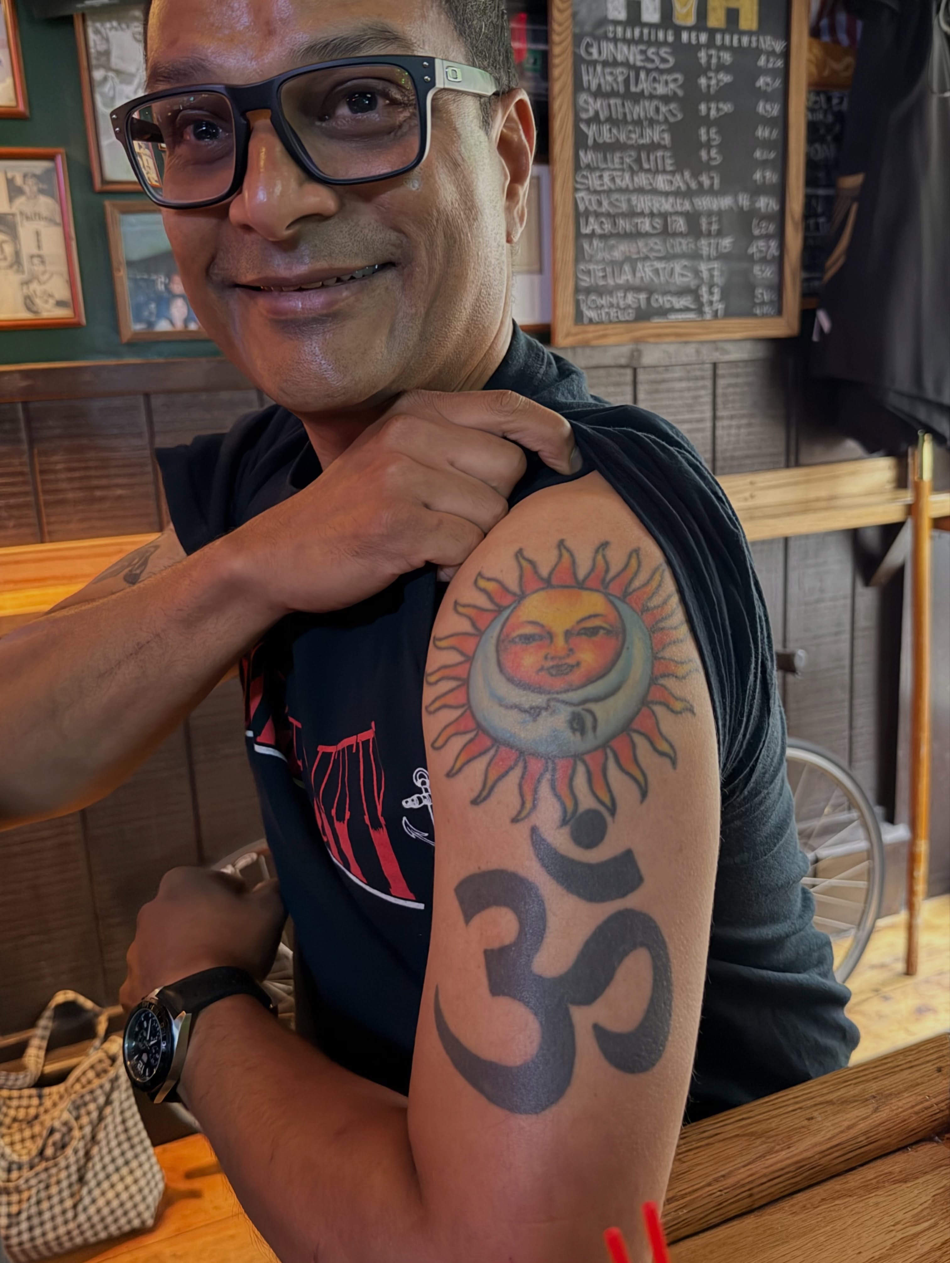 Sun and om symbol American traditional tattoo on the upper arm by Steve Tiberi