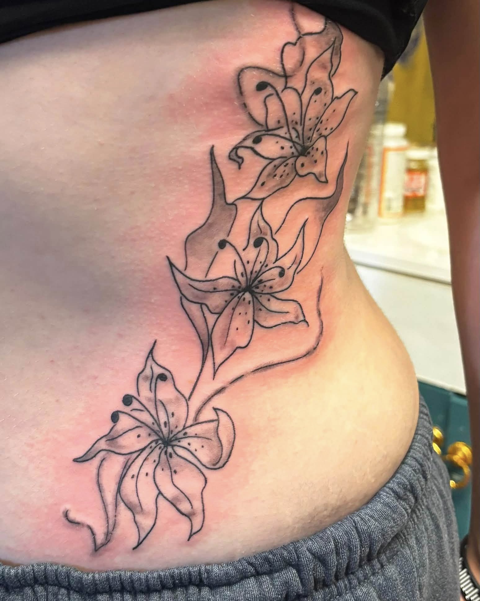 Lilies black and grey tattoo on the ribs by Jeff Zuptich