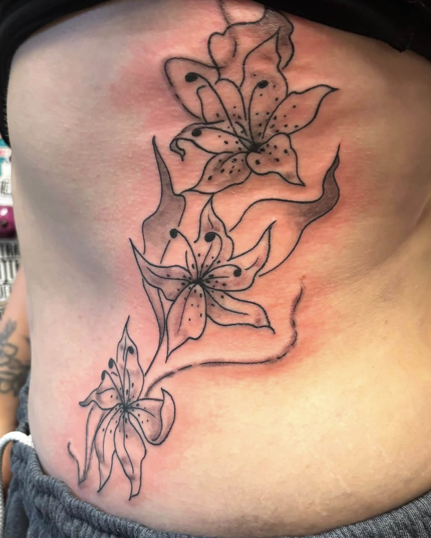 Lilies black and grey tattoo on the ribs by Jeff Zuptich