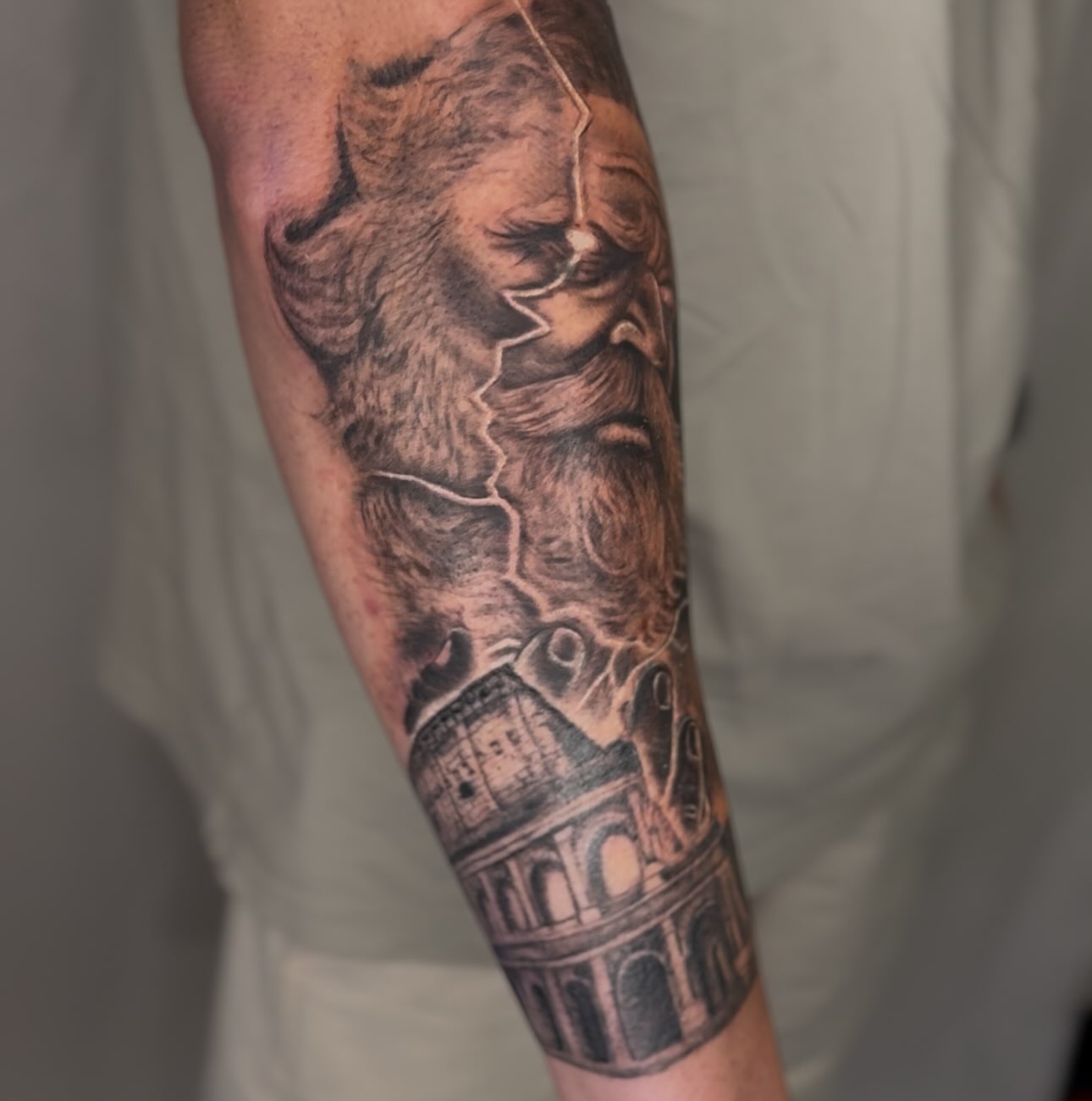 Ancient god and colosseum realism tattoo on the forearm by Elmer Lethco