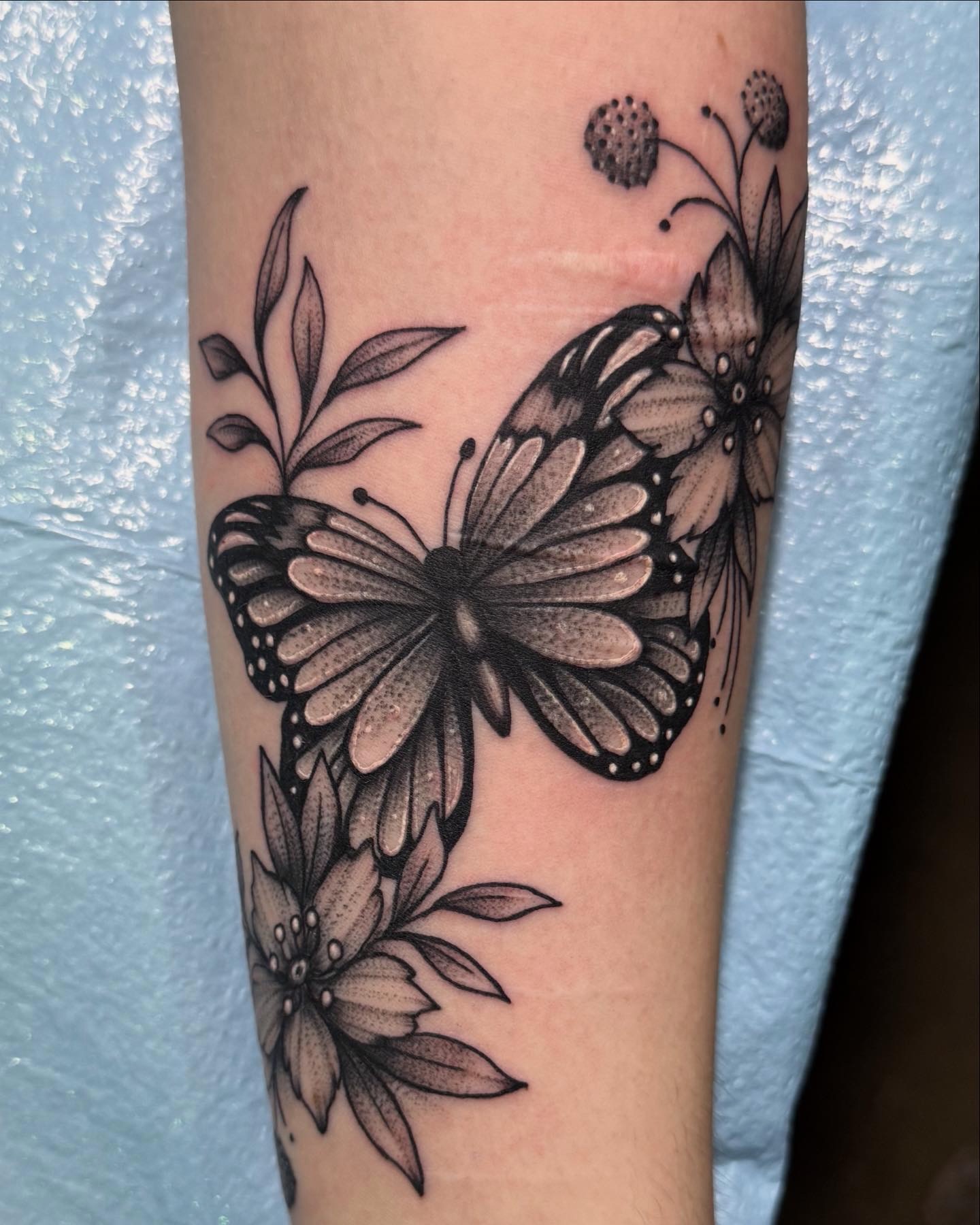 Butterfly and flowers dotwork tattoo on the forearm by Kirsten Cameron