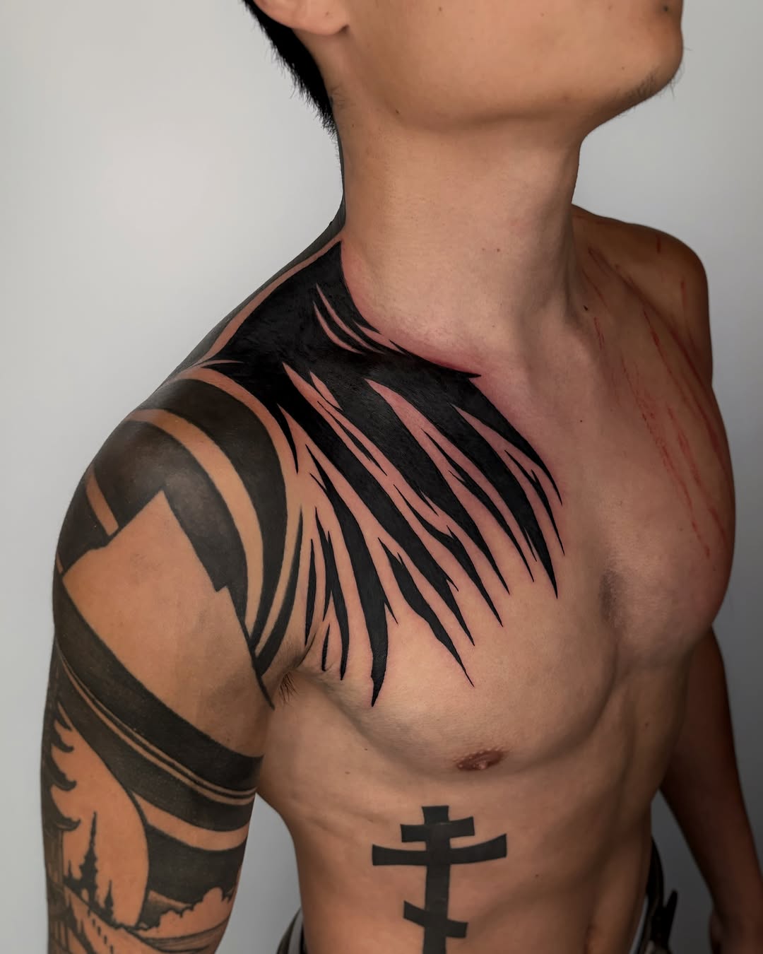 Feather tribal tattoo on the chest by Kuya, Berkeley, California
