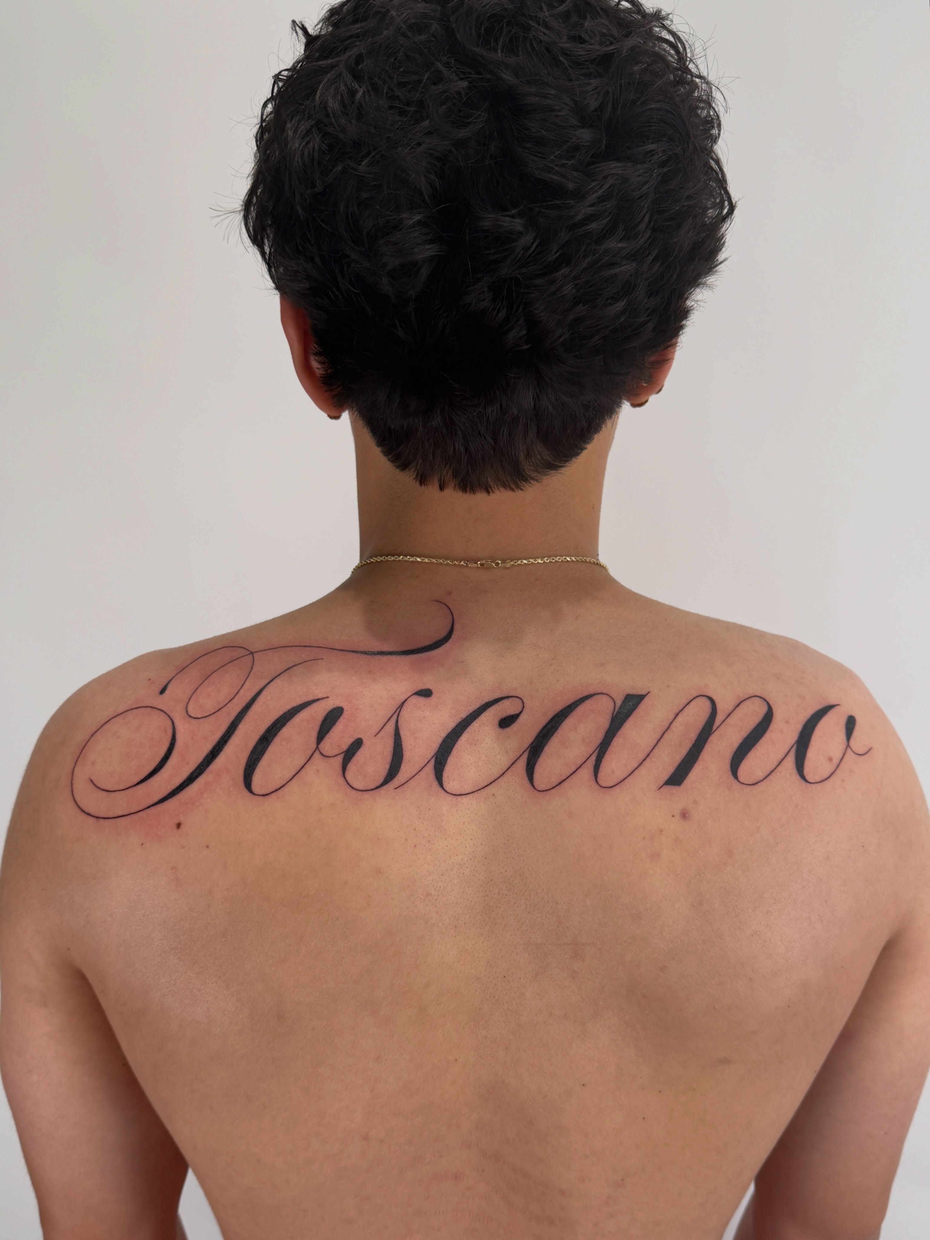 Toscano lettering script tattoo on the back by Alex