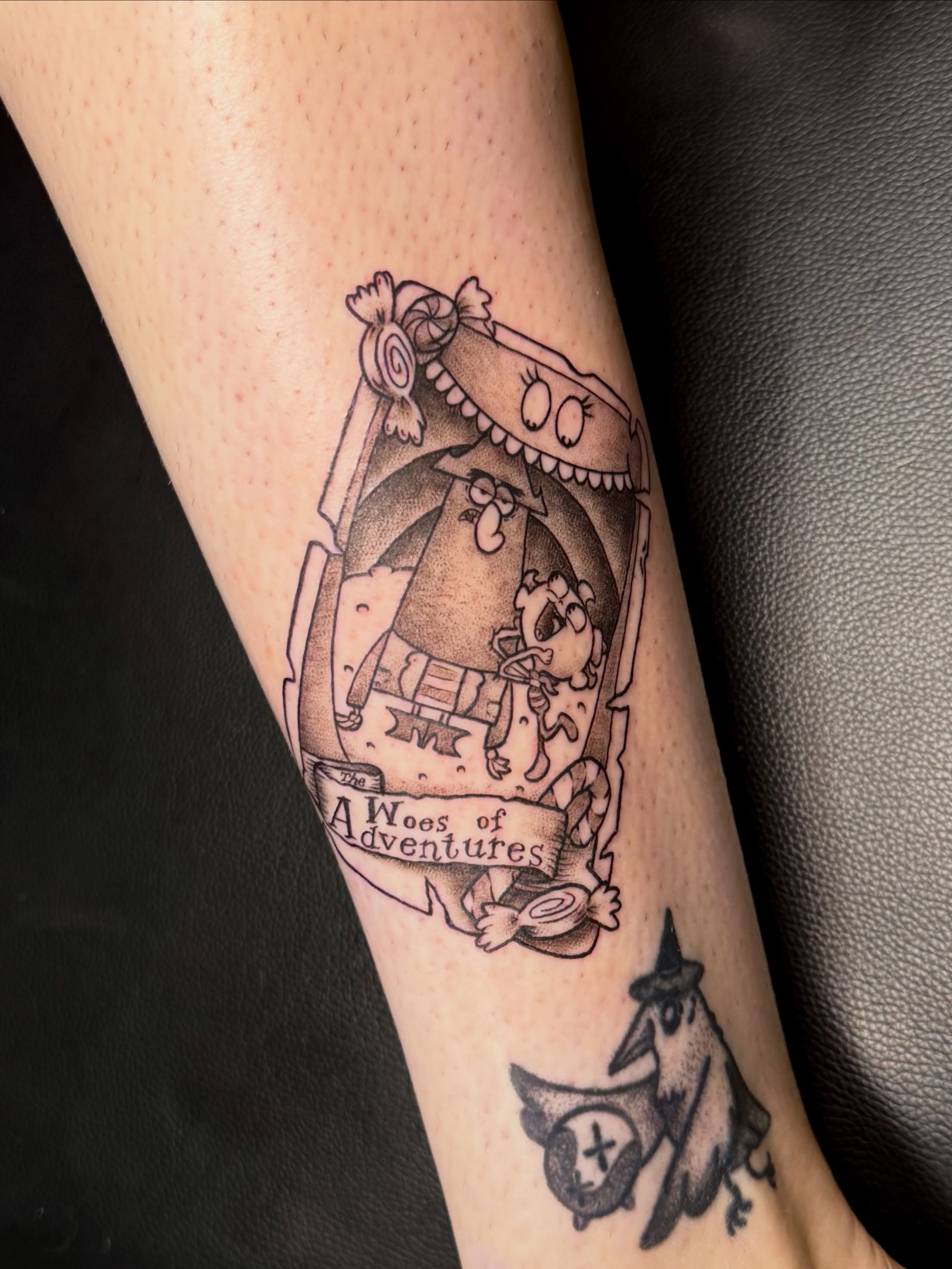 Cartoon characters black and grey tattoo on the forearm by Taylor Kay 🌿
