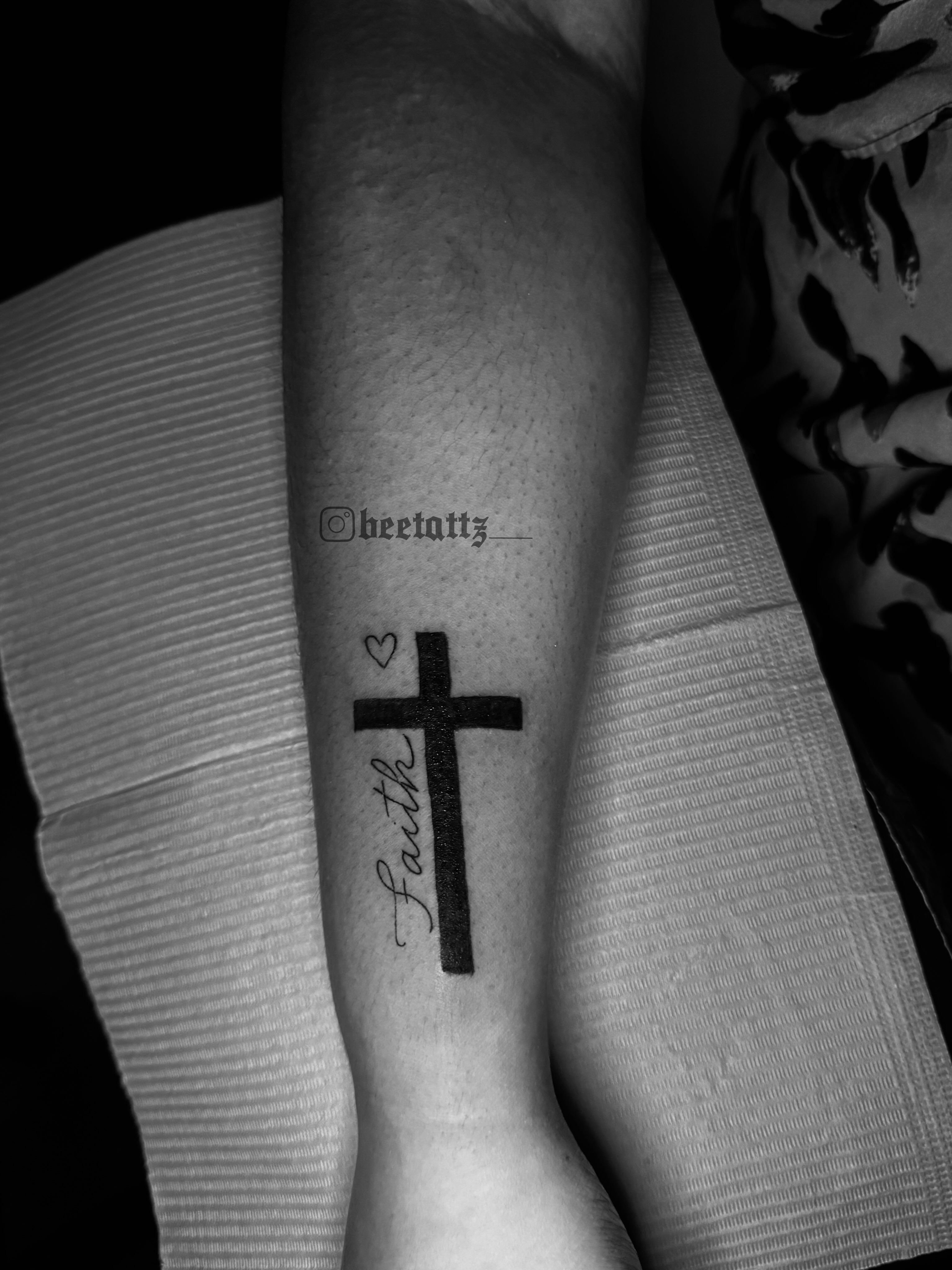 Cross with 'Faith' black and grey tattoo on the forearm by Brinkley McGill