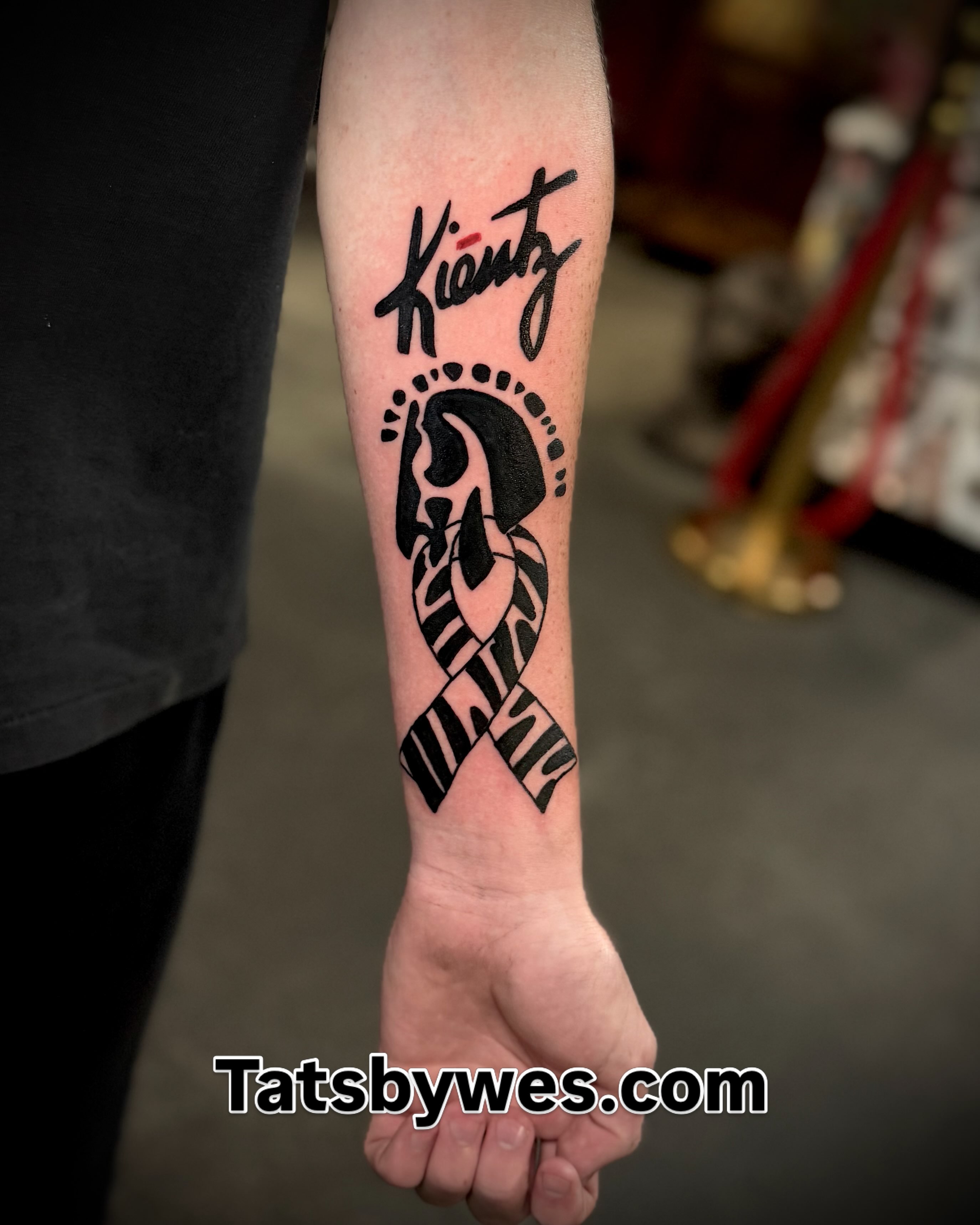 Footprint and ribbon black and grey tattoo on the forearm by 𝐖𝐄𝐒