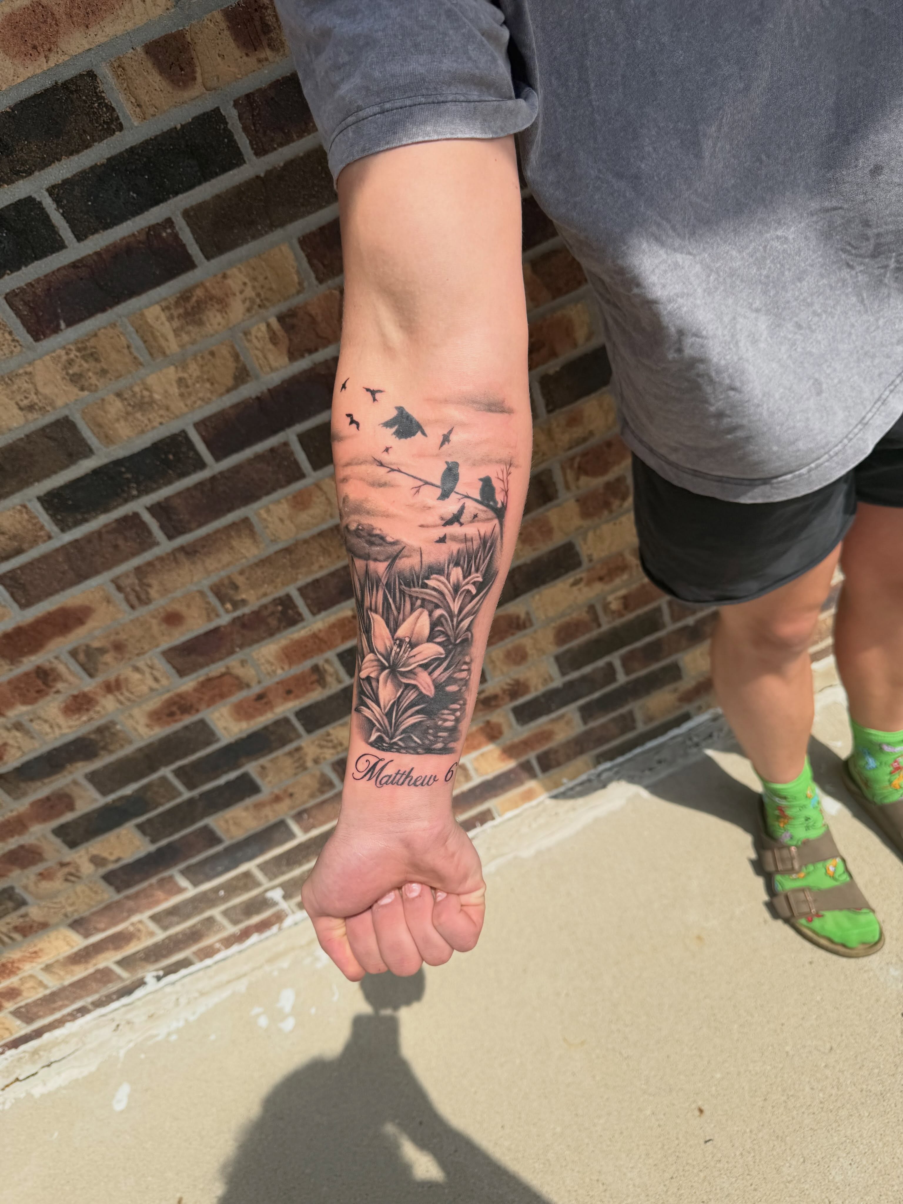 Bird and lily black and grey tattoo on the forearm by Lauren Horness