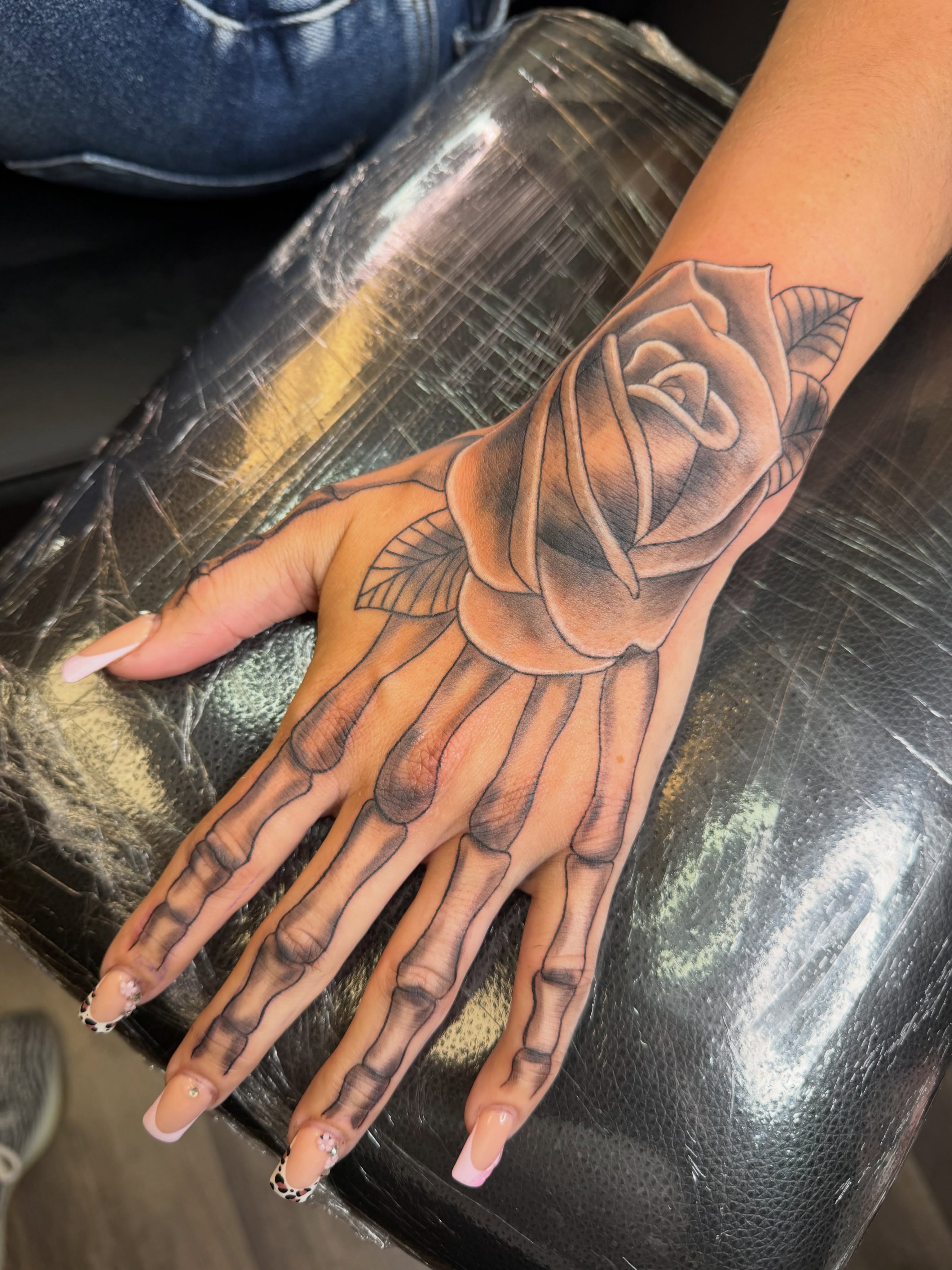 Skeleton hand with rose realism tattoo on the hand by Rain David