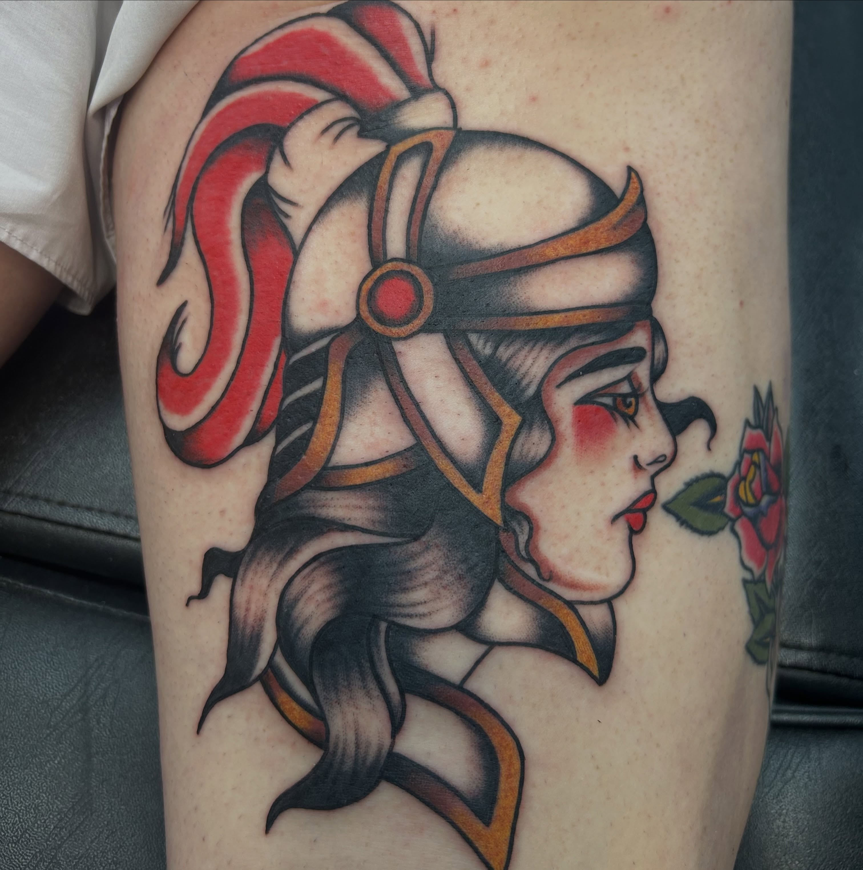 Woman with helmet and rose American traditional tattoo on the thigh by Dylan James