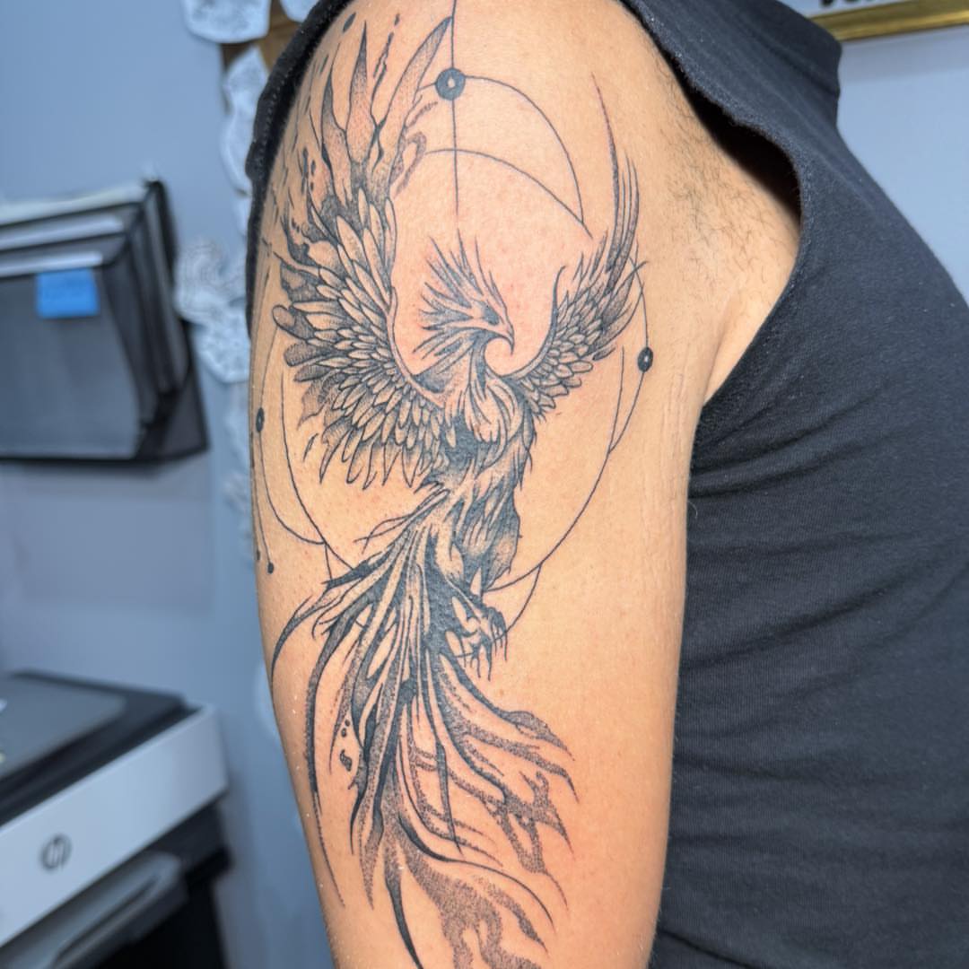 Phoenix black and grey tattoo on the upper arm by Destiny A