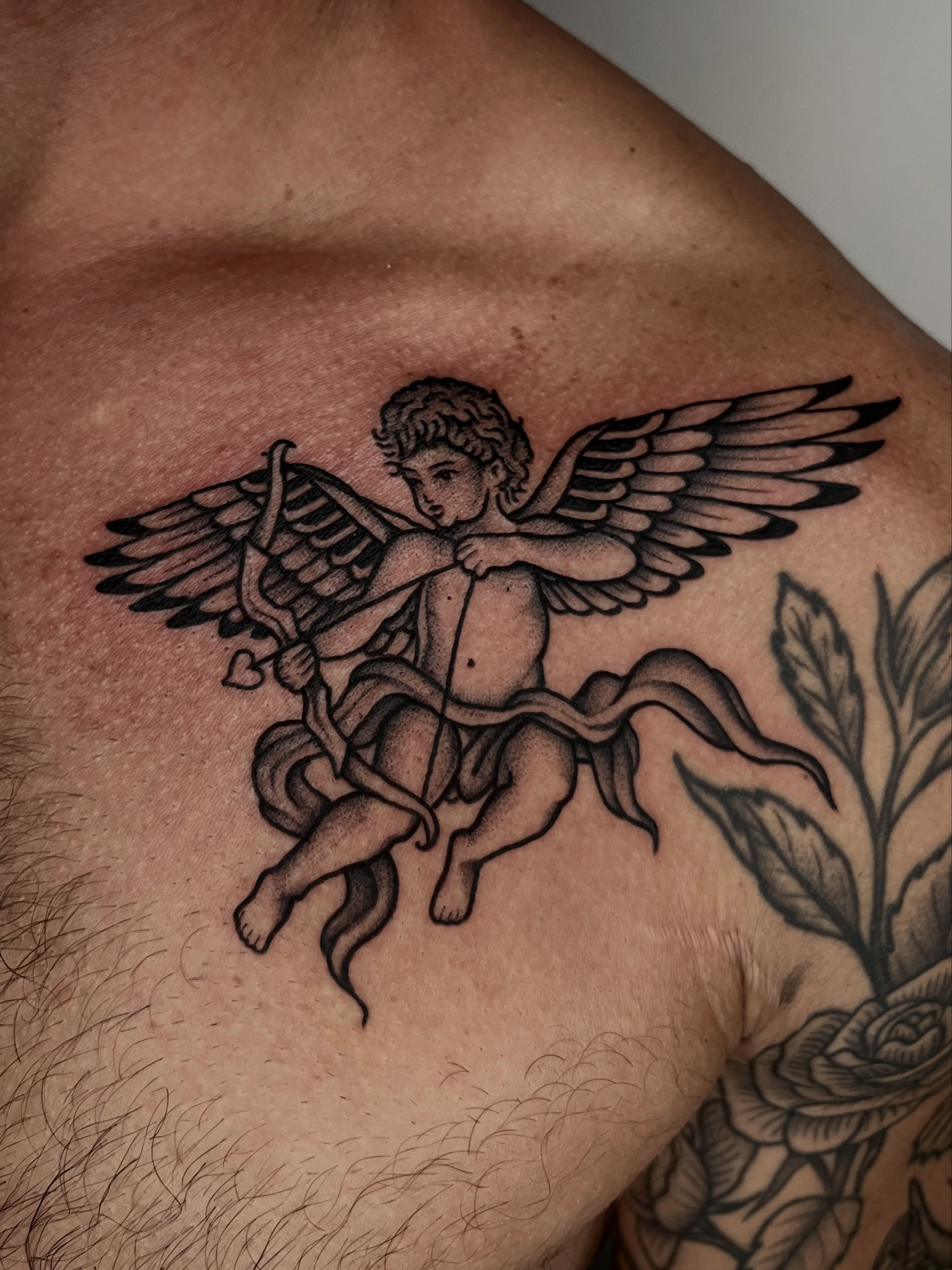 Cherub with bow and arrow black and grey tattoo on the chest by Patrick Elijah