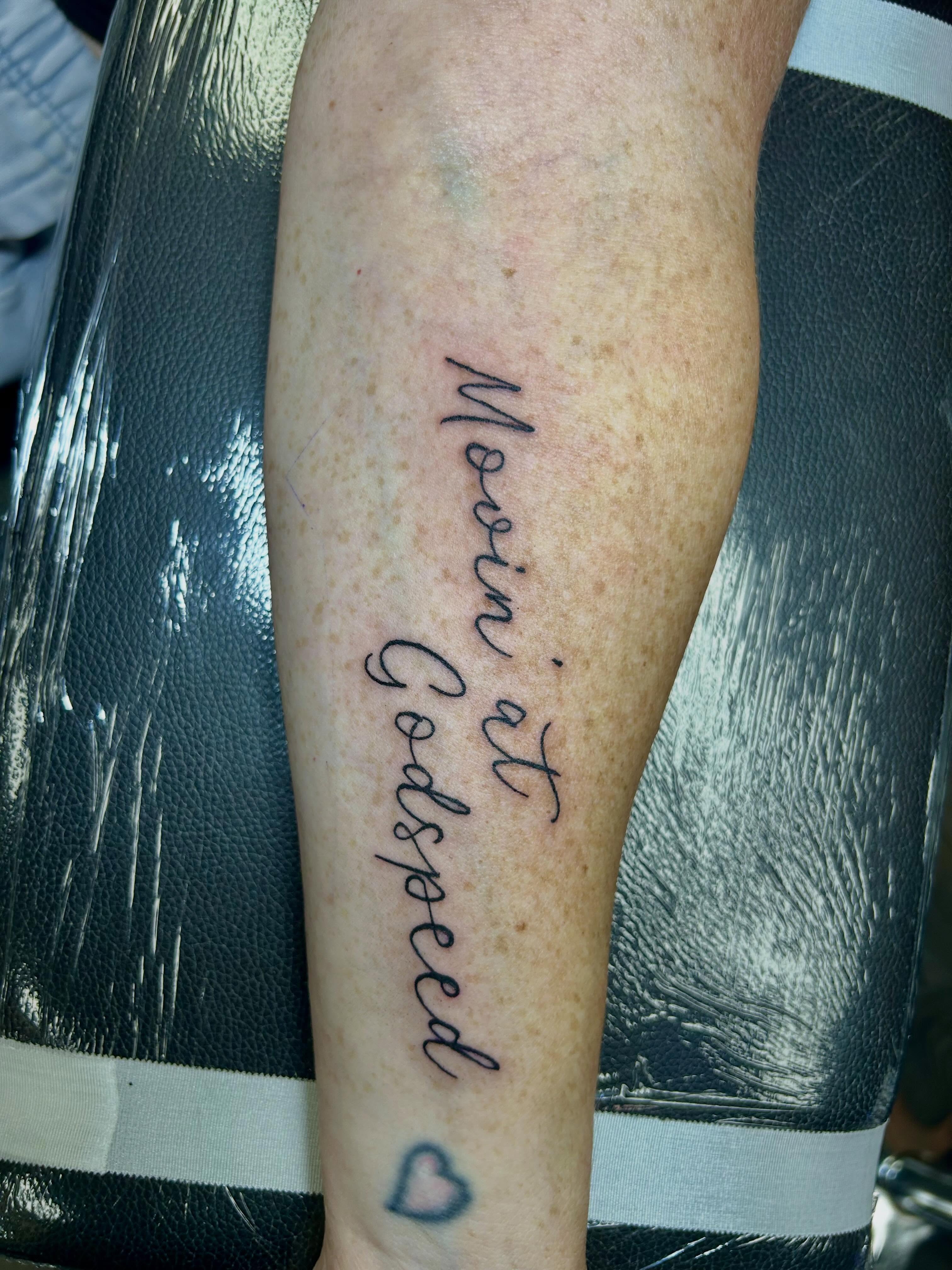 Movin' at Godspeed lettering script tattoo on the forearm by Bjorn Bjornstad, Dubuque, Iowa