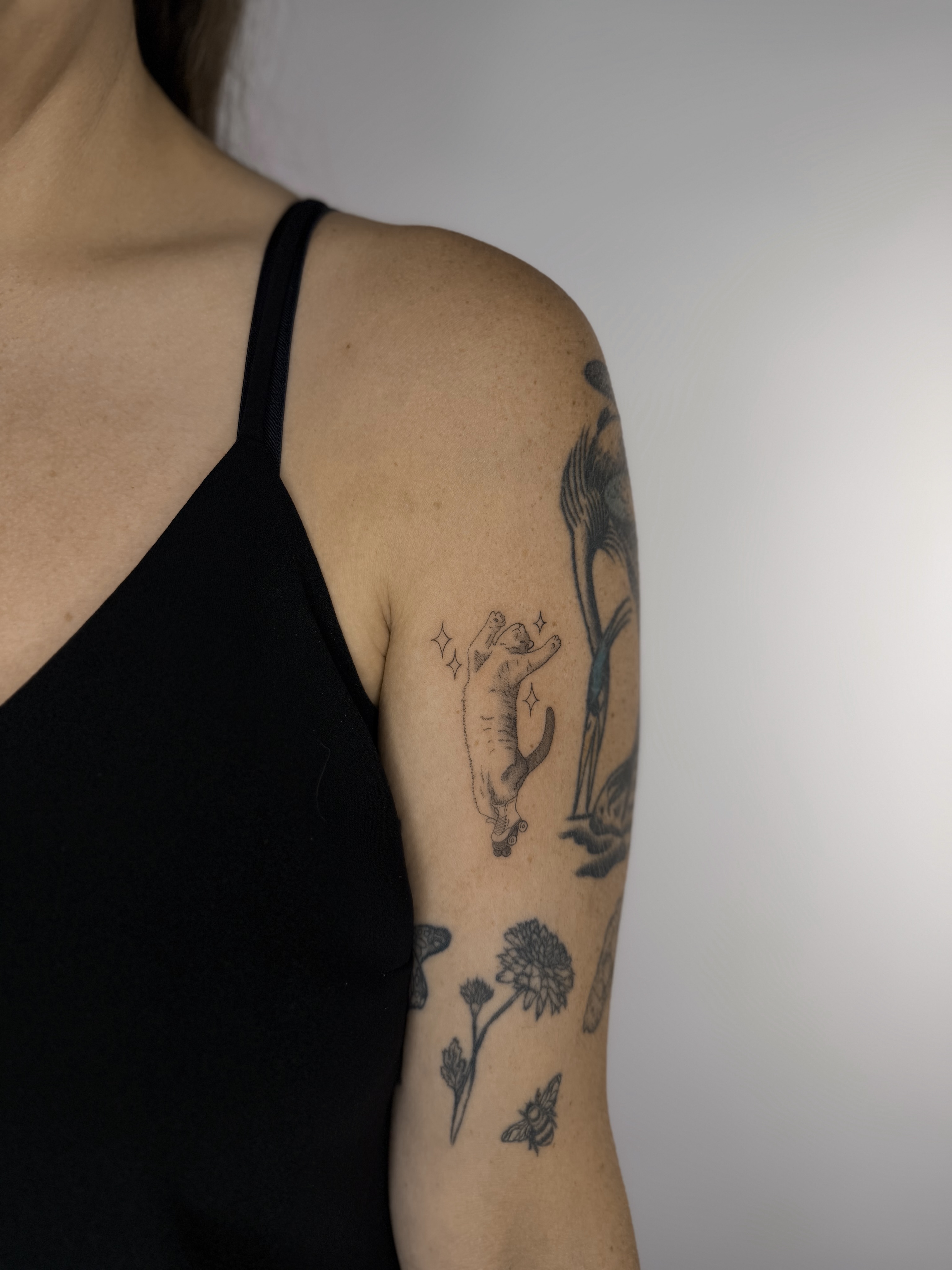 Cat and flowers black and grey tattoo on the upper arm by Fineline Tattoos DFW