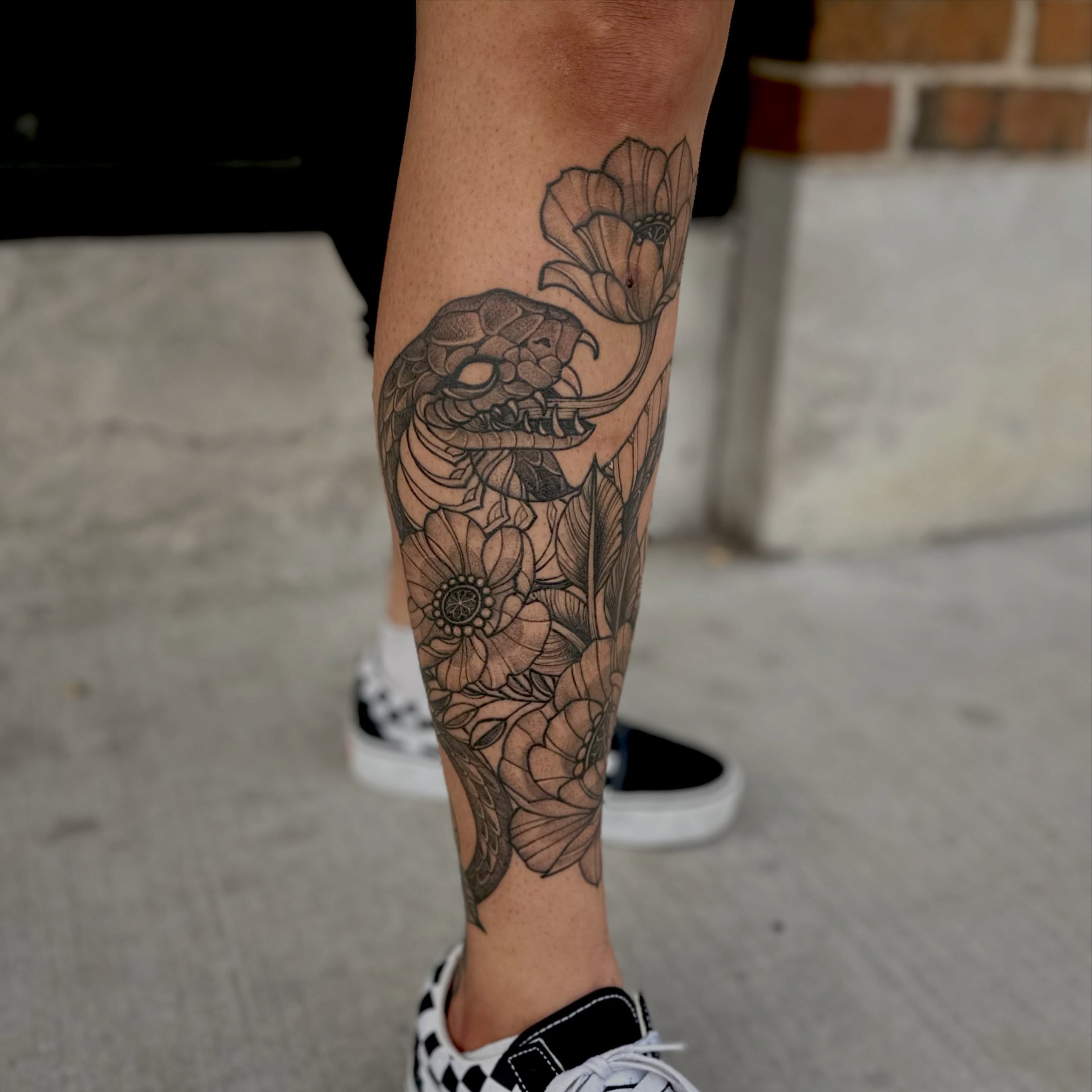 Snake and flowers black and grey tattoo on the forearm by Leeuh Vandever