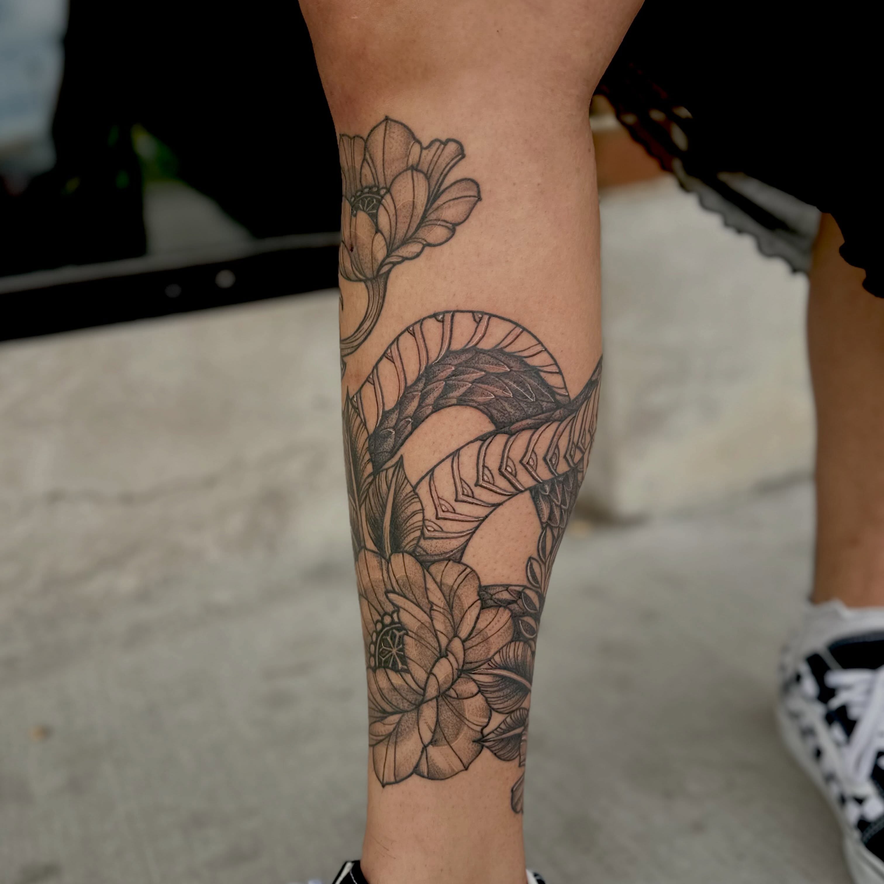 Snake and flowers geometric tattoo on the forearm by Leeuh Vandever