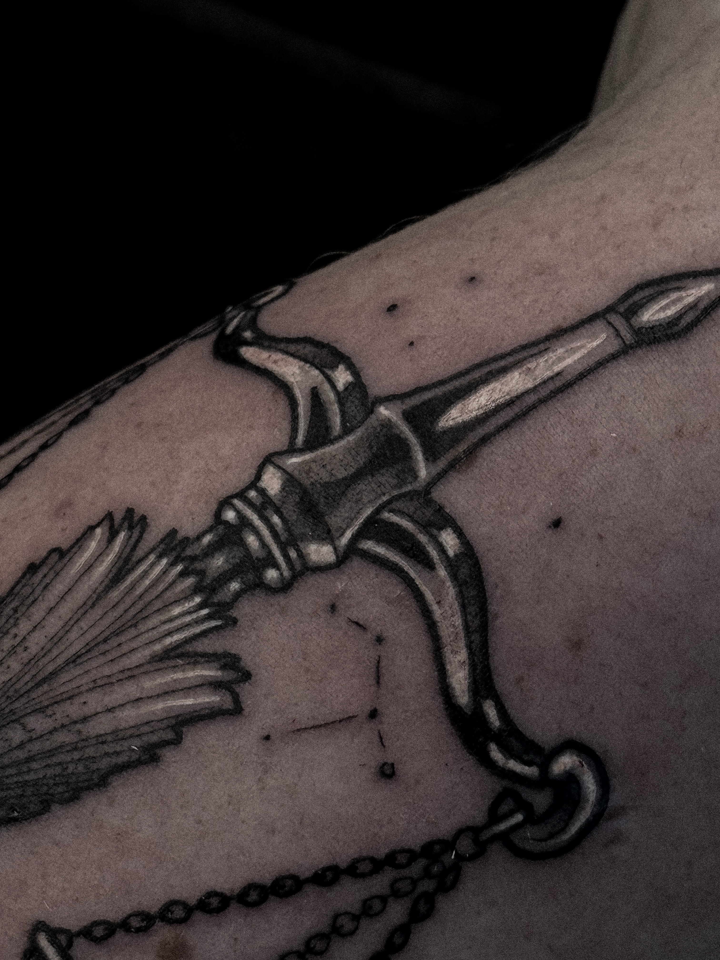 Tassel and hook black and grey tattoo on the forearm by Dane Bezeau
