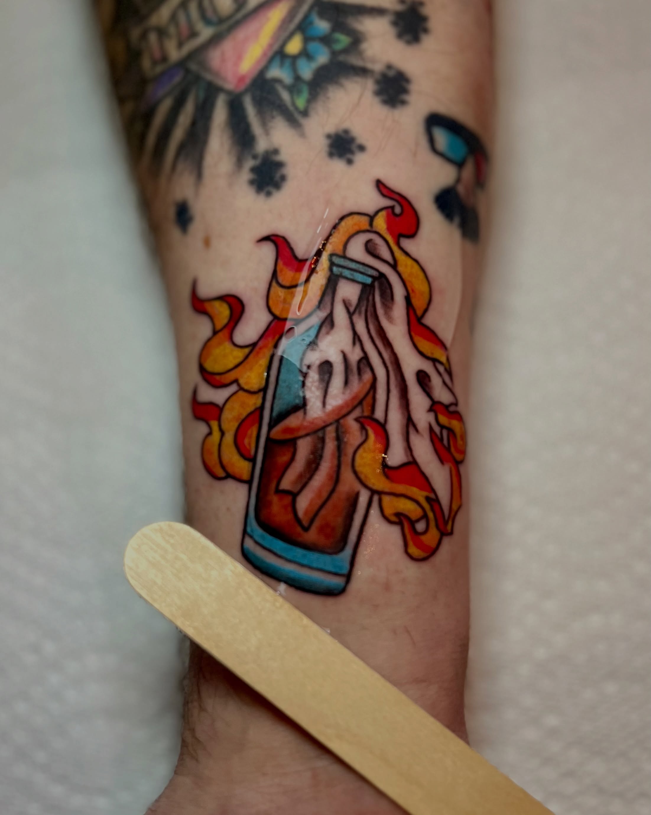 Flaming bottle new school tattoo on the forearm by EO, Chicago, Illinois
