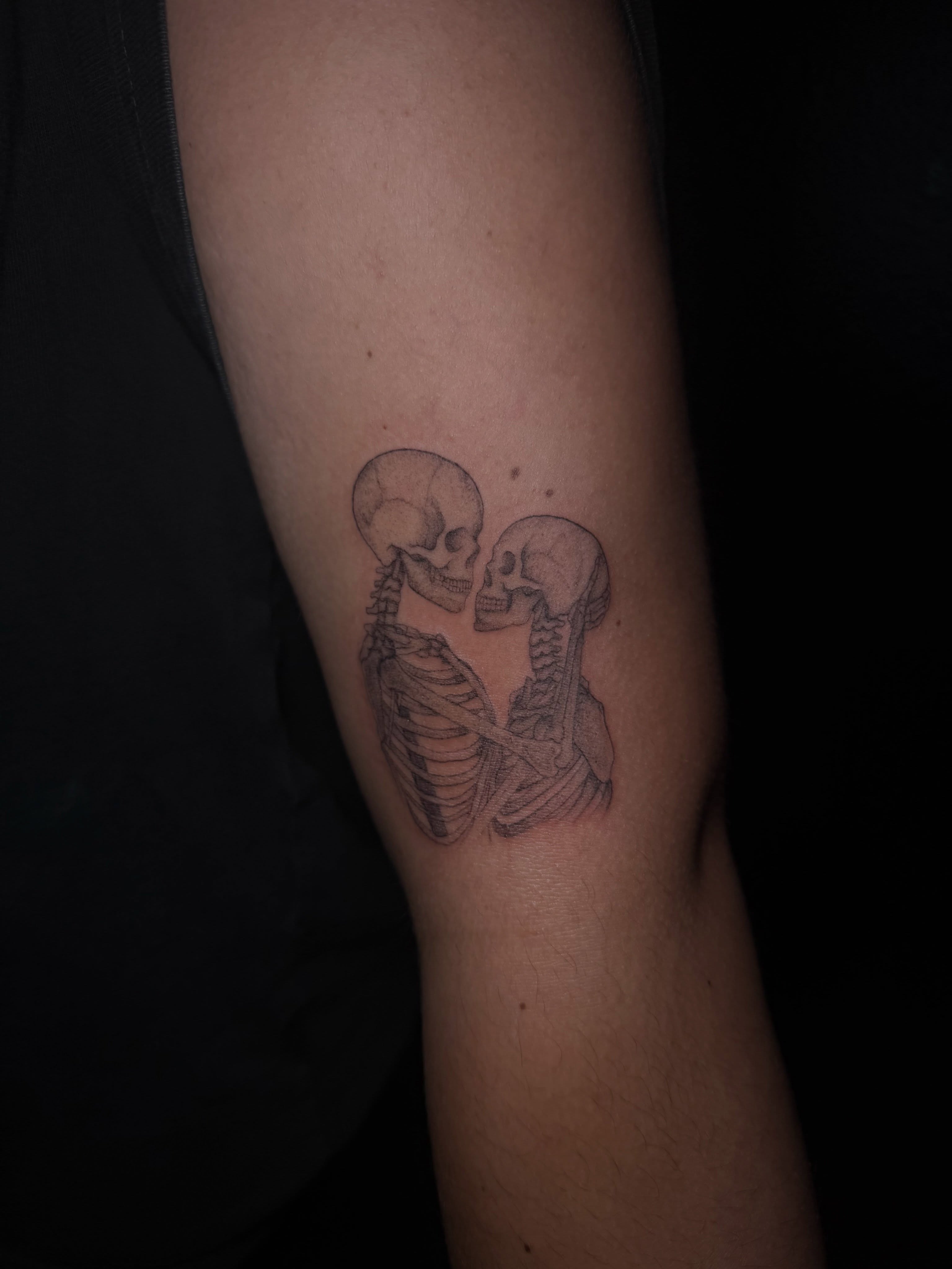 Skeletons kissing black and grey tattoo on the forearm by Ink Darling, Carlisle, Iowa