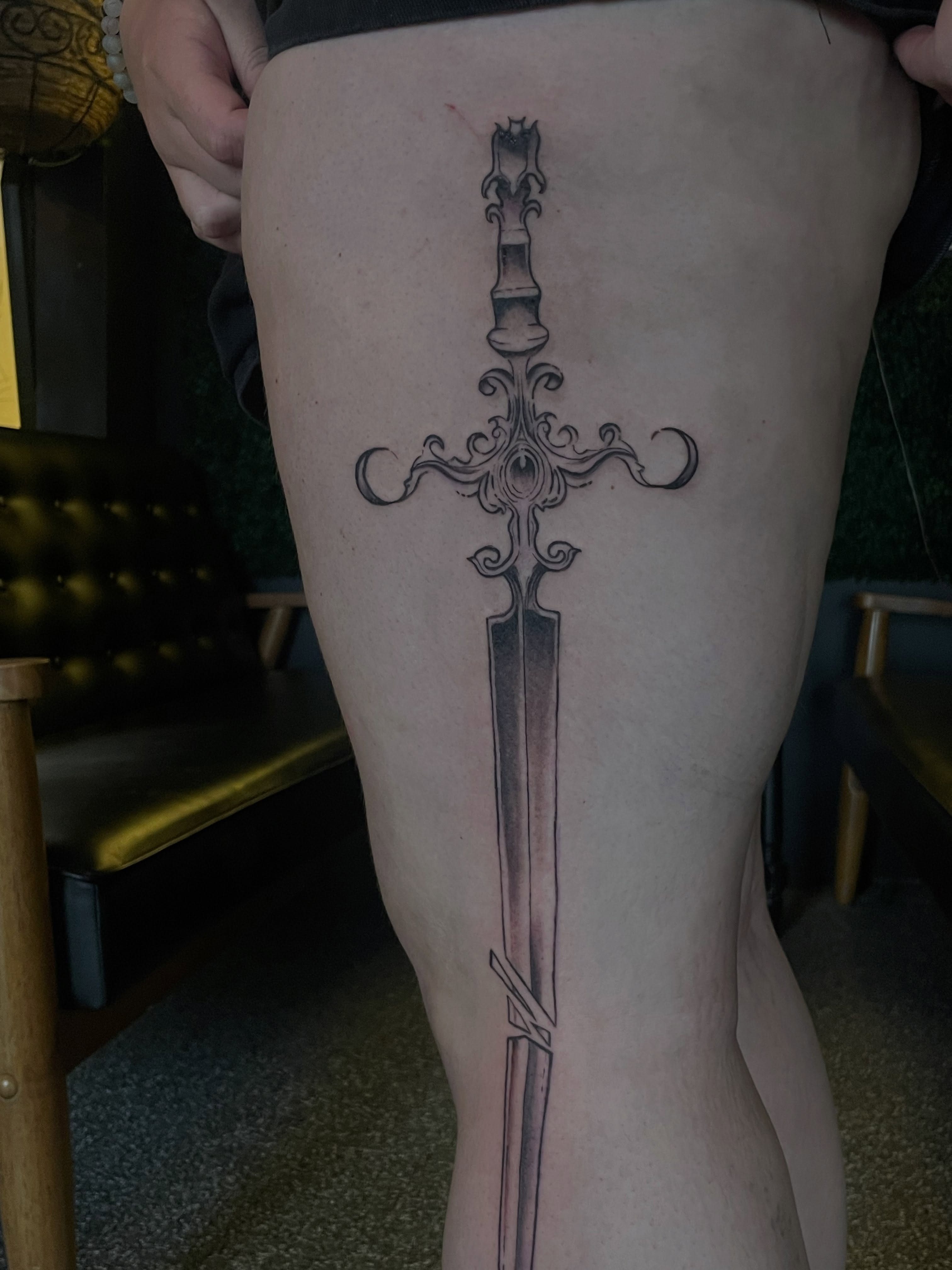 Sword black and grey tattoo on the thigh by Trinity