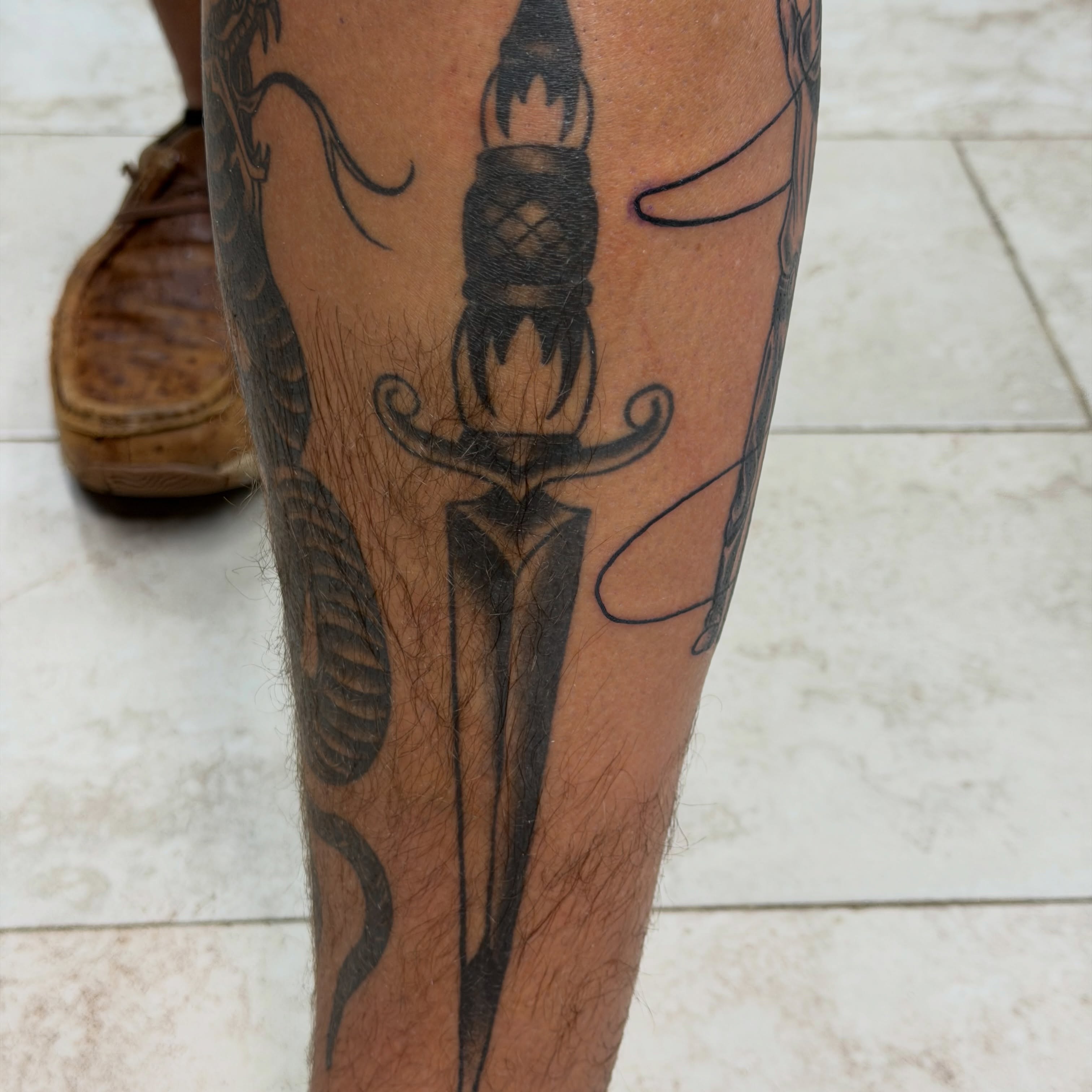 Rocket and sword black and grey tattoo on the calf by Squid