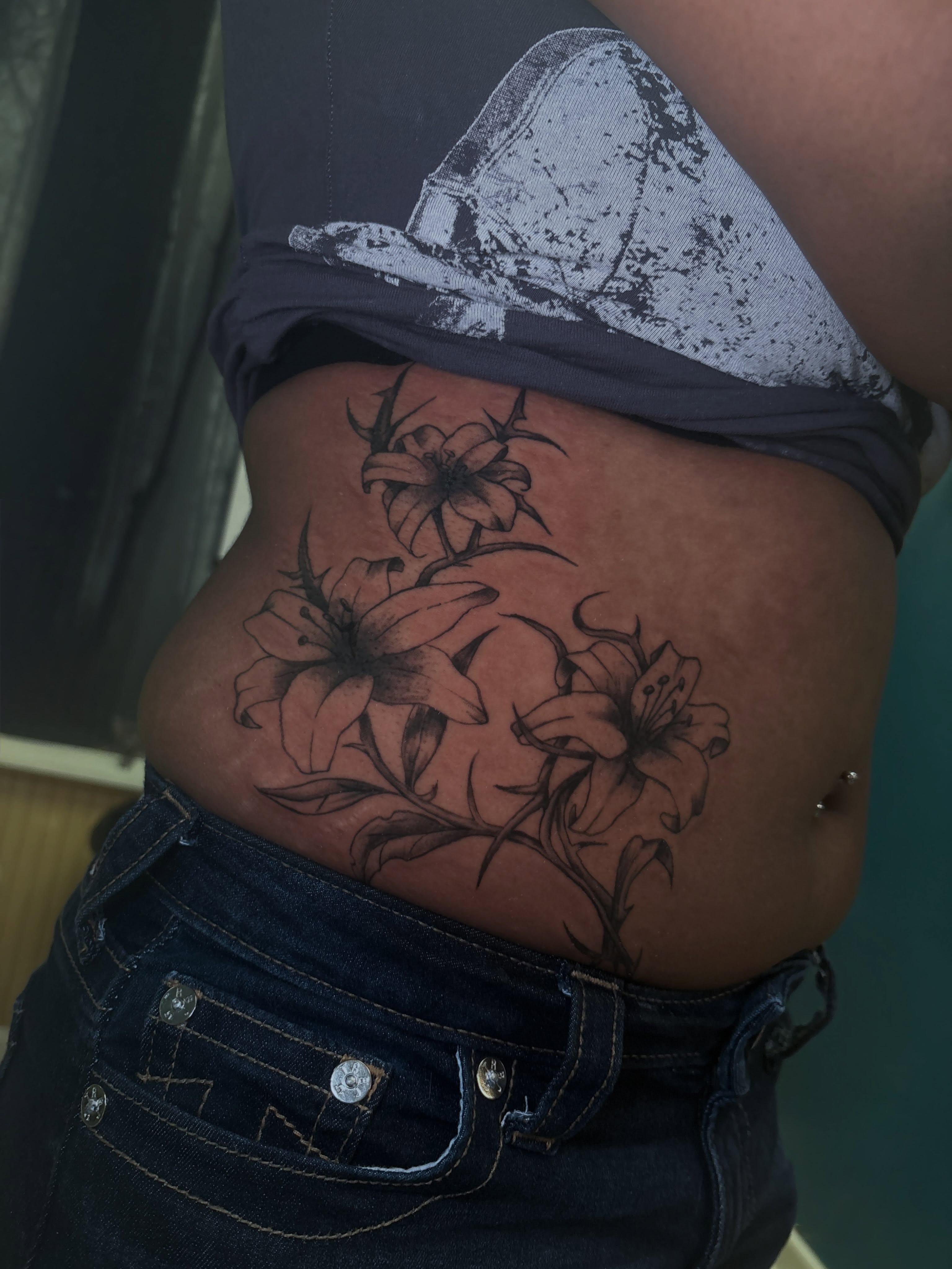 Lilies black and grey tattoo on the torso by ⋆.˚ ☾ .⭒˚ alaina