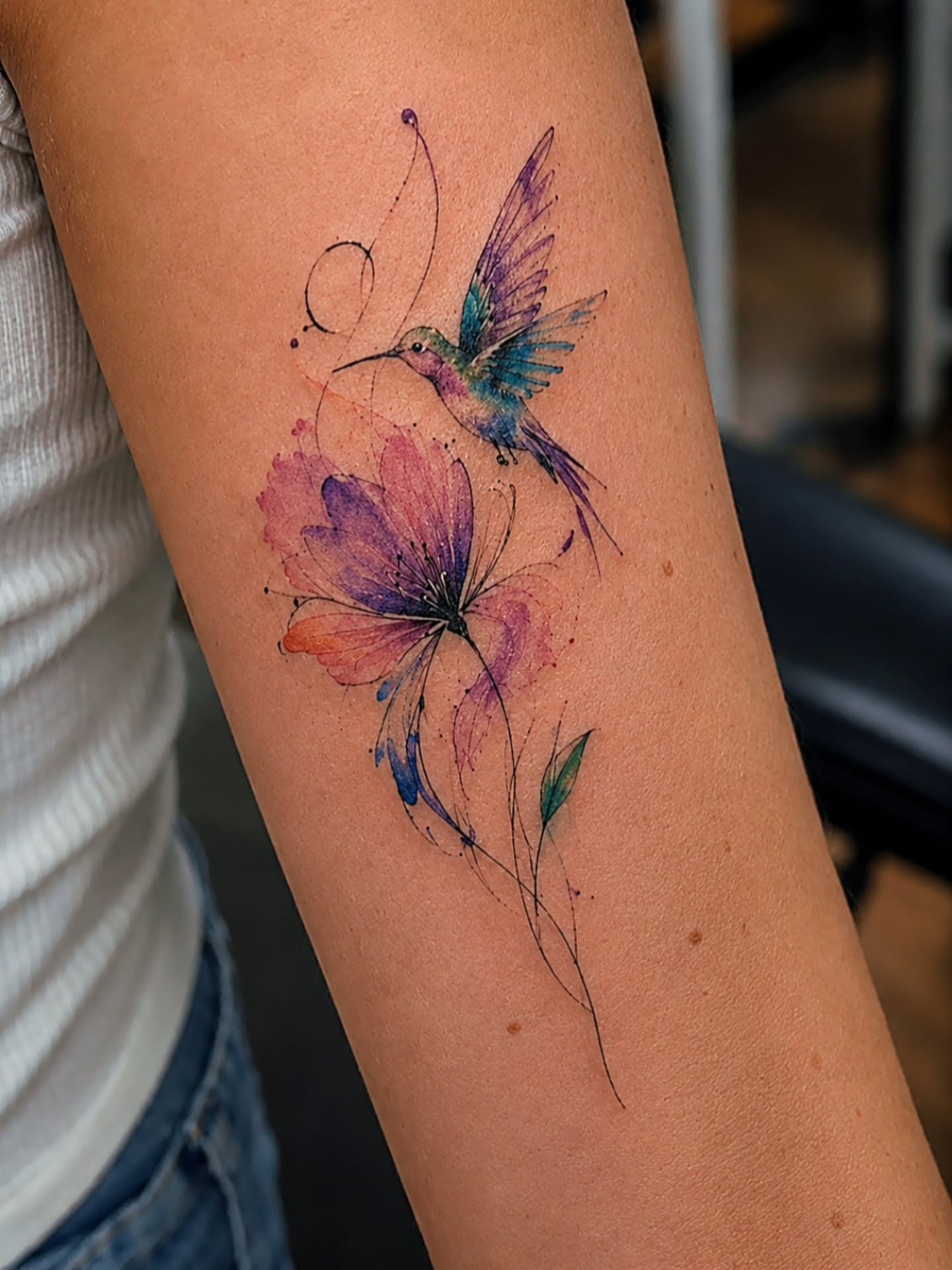 Hummingbird and flower watercolor tattoo on the forearm by Dr. Valerio Vegas Tattoo