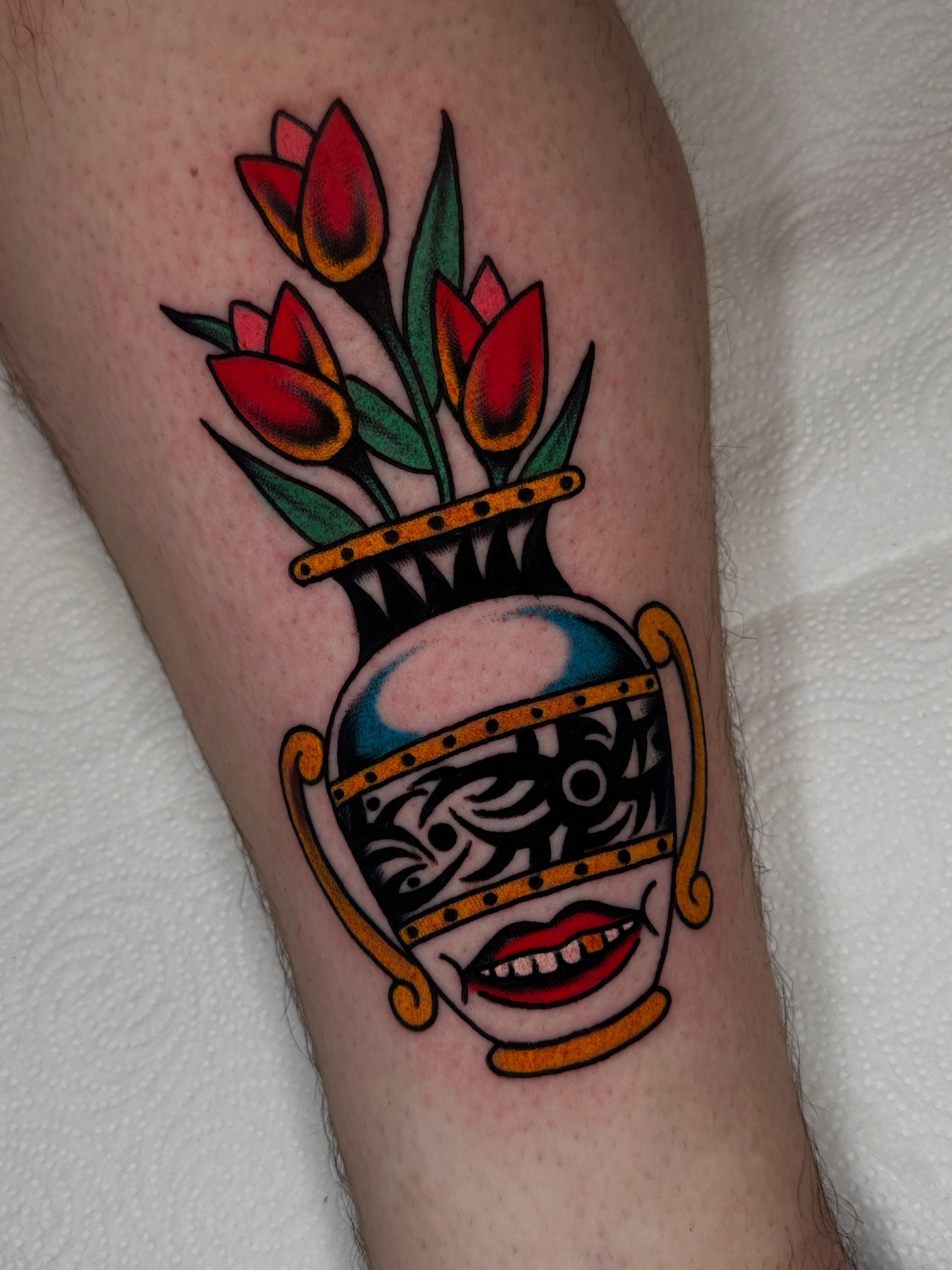 Mask with flowers American traditional tattoo on the forearm by Spencer Crawford, Speedway, Indiana