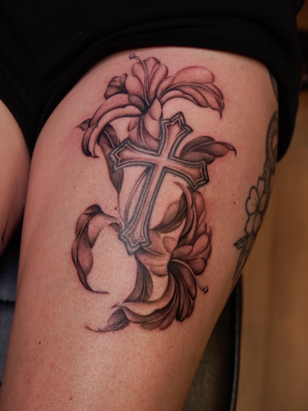 Cross with lilies black and grey tattoo on the thigh by Nicki Yến