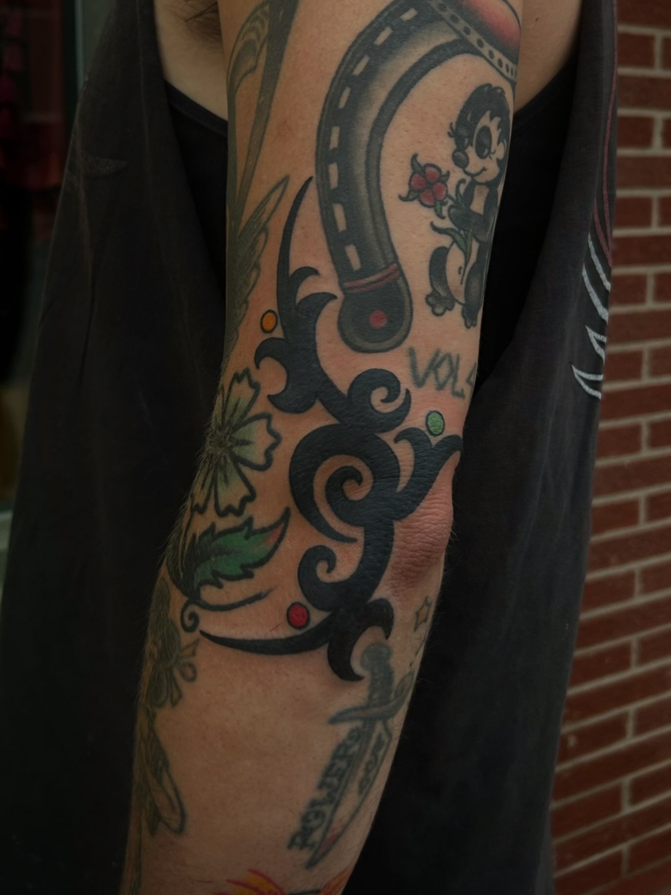 Film reel and character American traditional tattoo on the forearm by ꧁𝙺𝚊𝚛𝚒𝚗𝚊꧂, Grinnell, Iowa