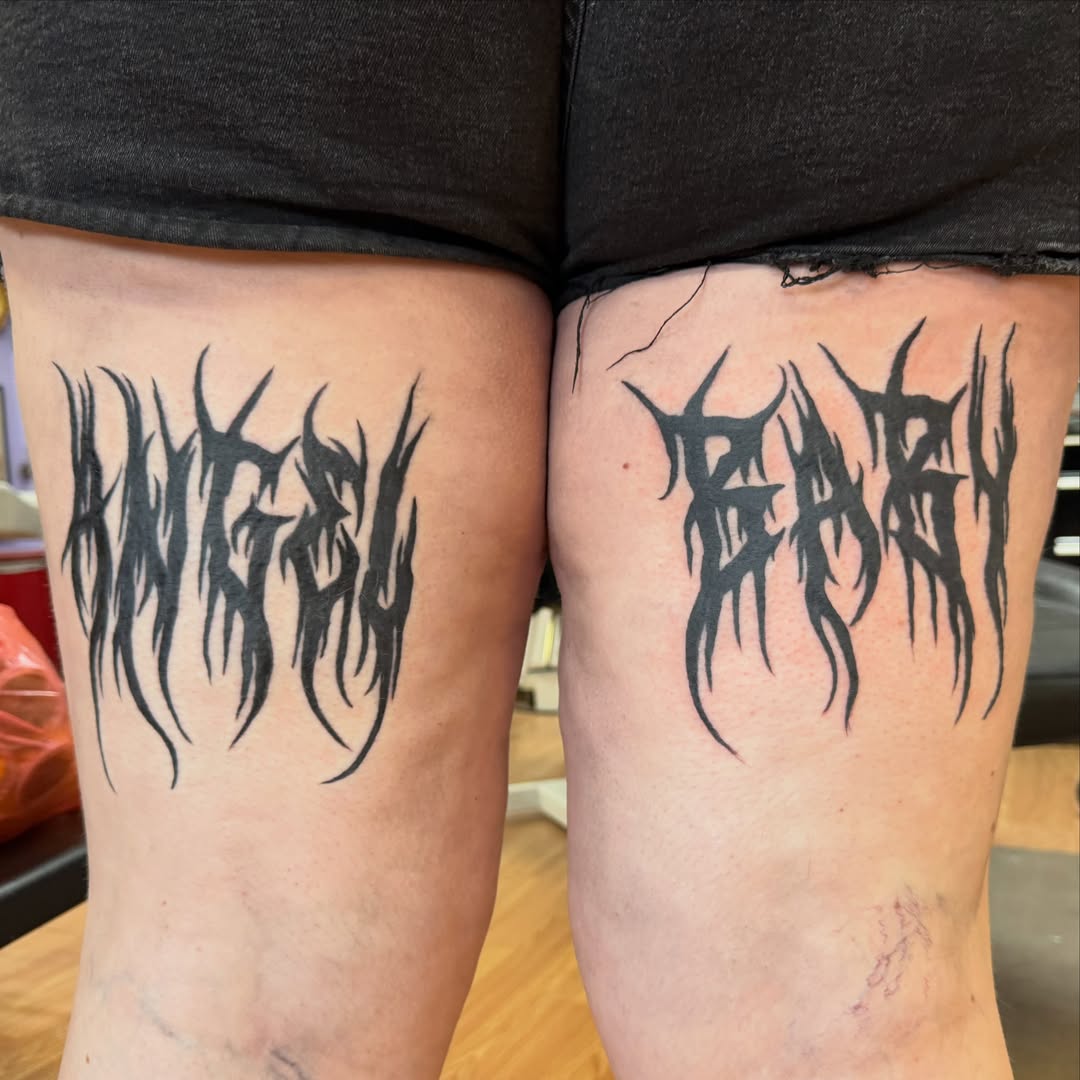 Lettering black and grey tattoo on the thigh by Justin Fiveson