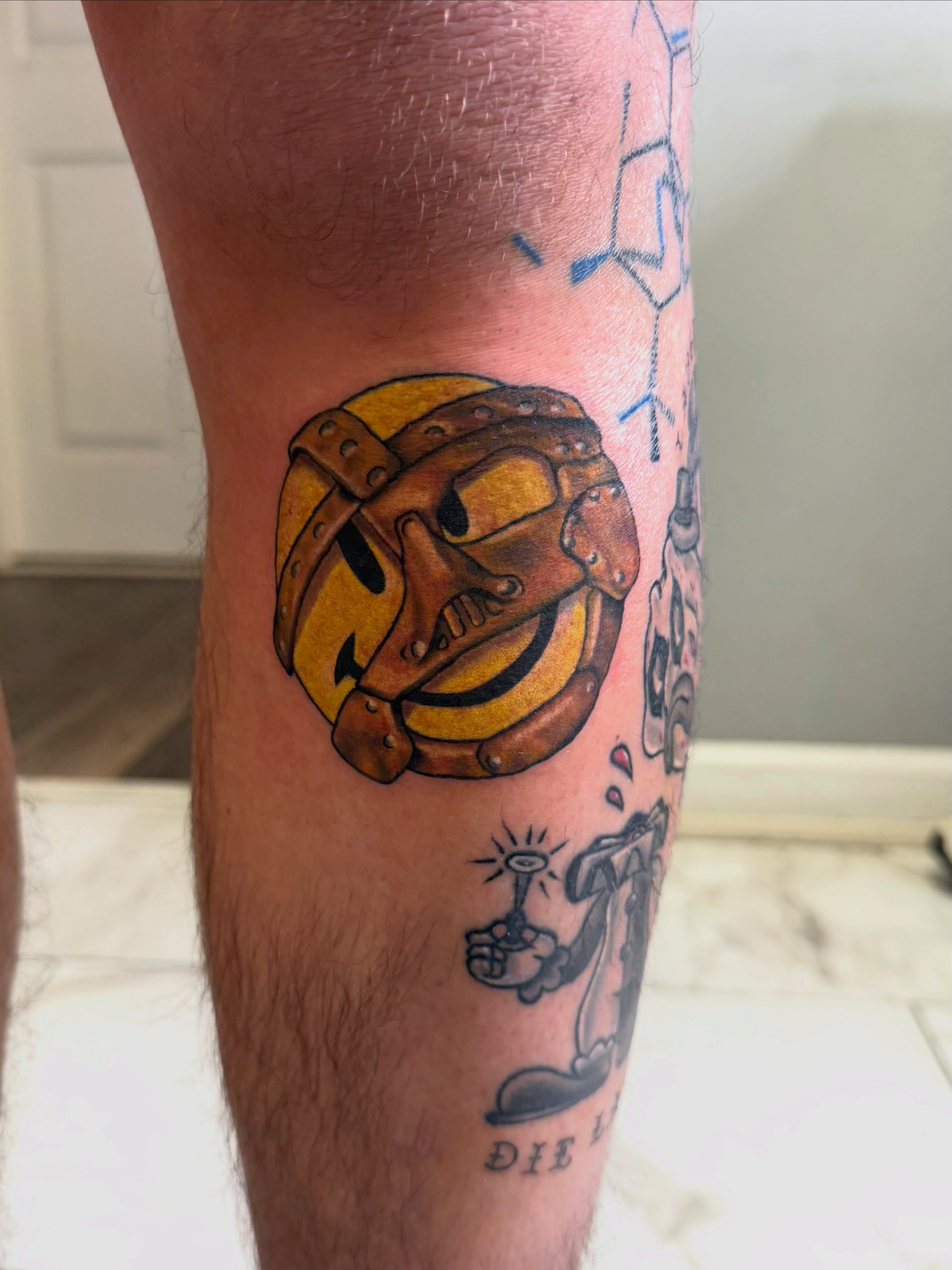 Smiley face helmet American traditional tattoo on the calf by linda perez