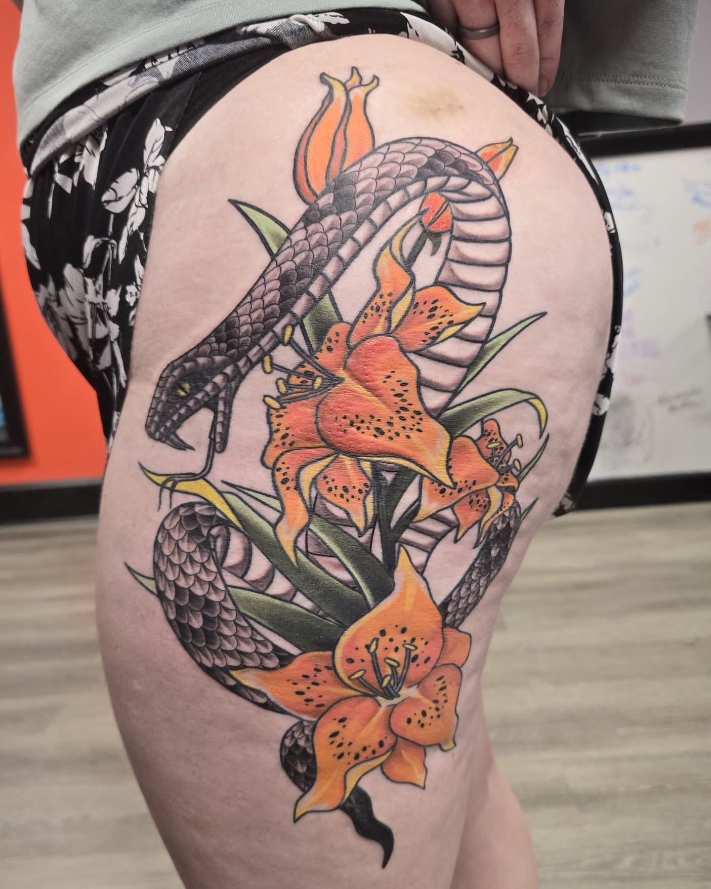 Snake and lilies American traditional tattoo on the thigh by Gene Britton