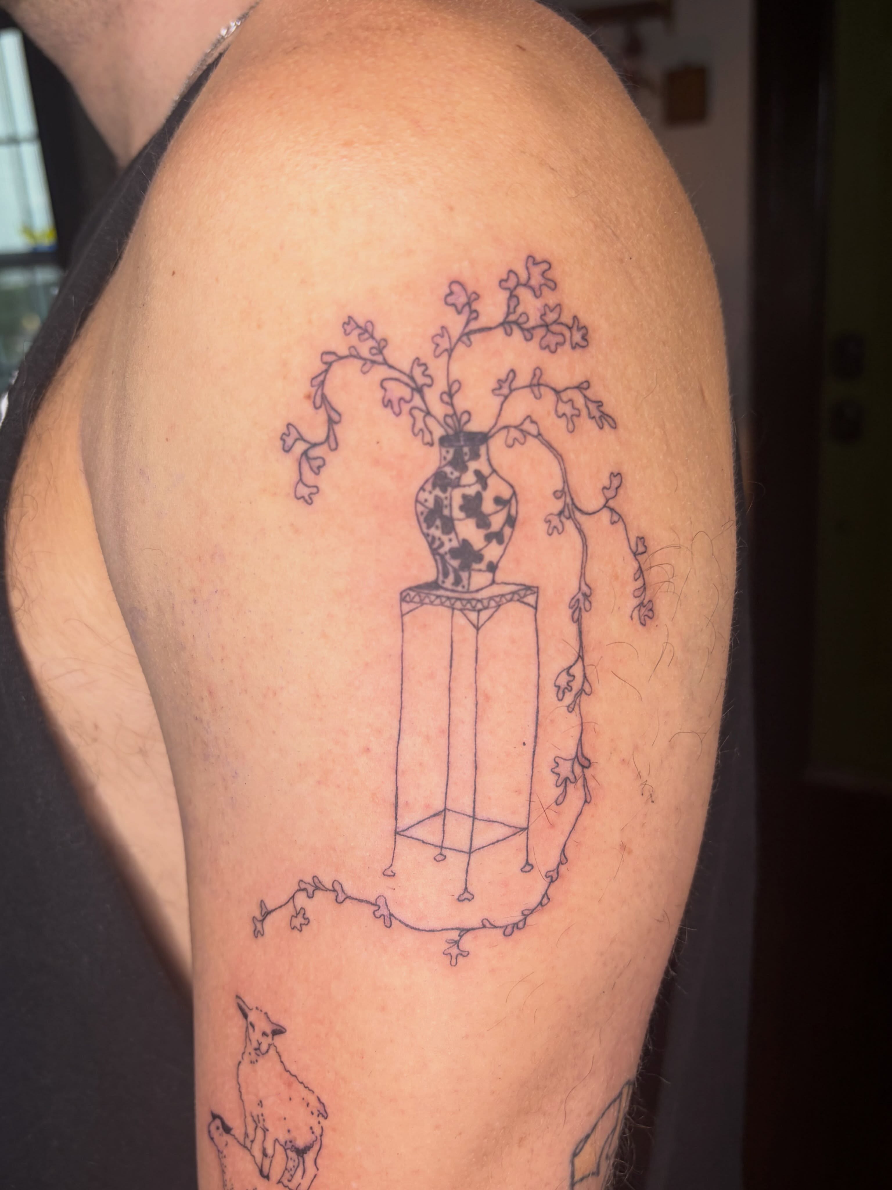 Vase with branches minimalist tattoo on the upper arm by Mattie Robinson