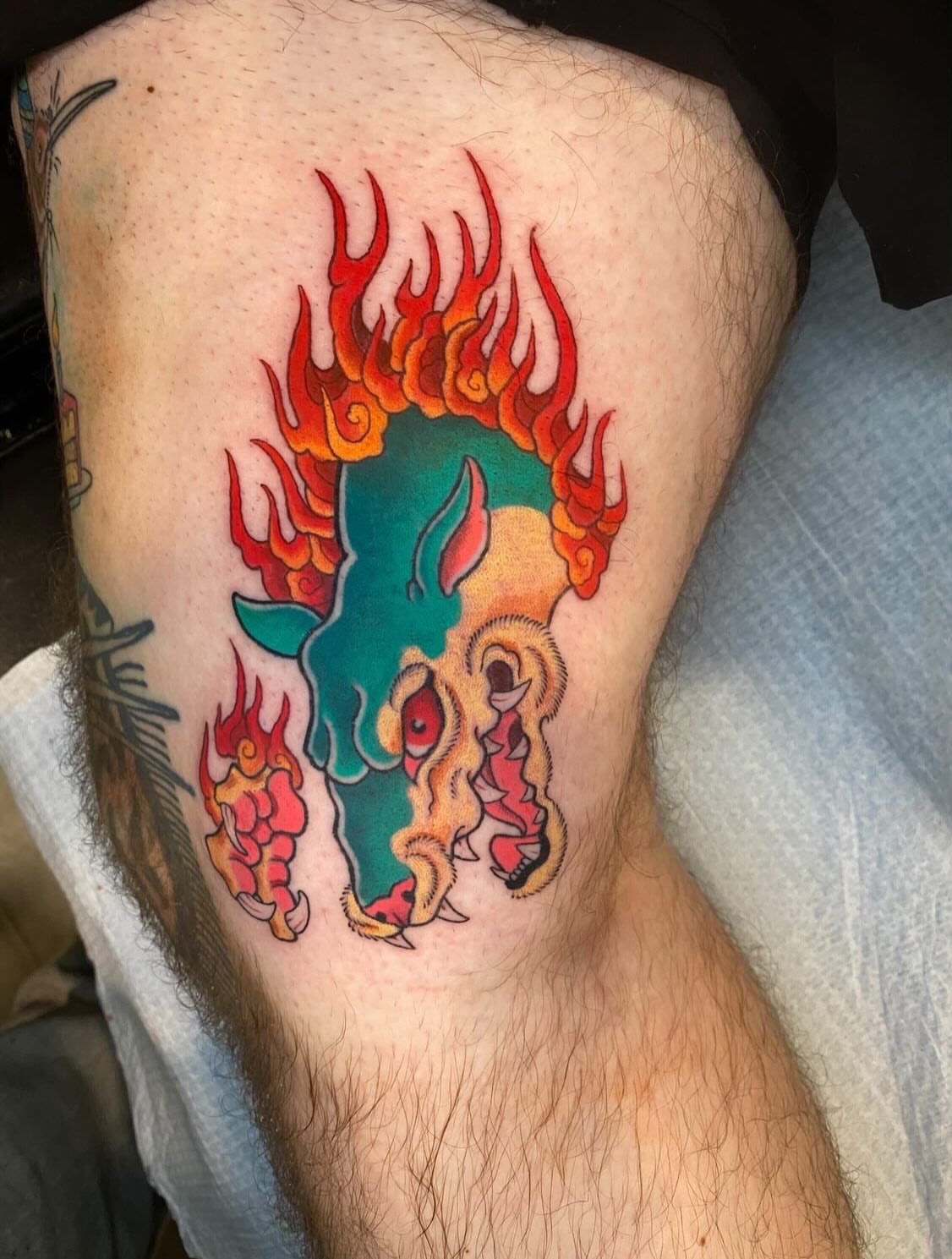 Bull skull with flames American traditional tattoo on the thigh by Mitch Bonifay