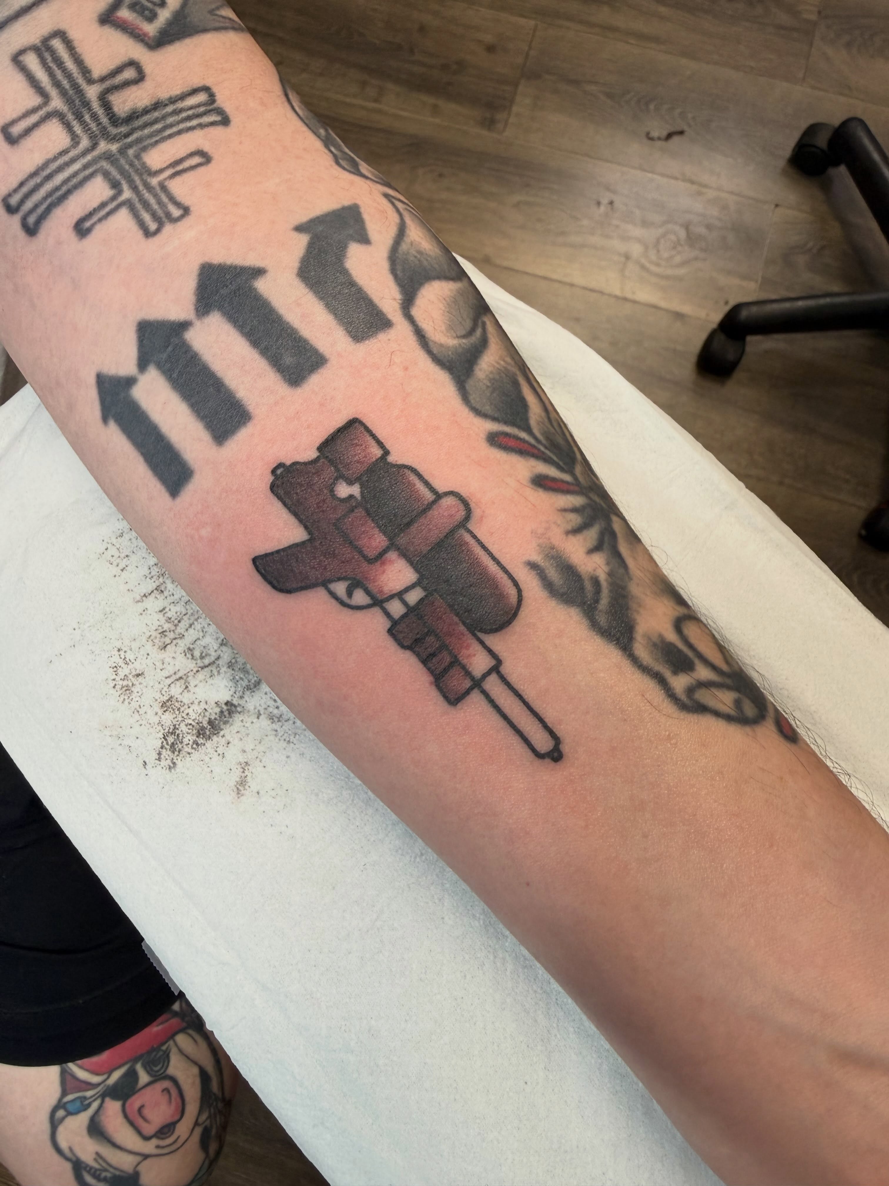 Gun and arrows American traditional tattoo on the forearm by Chase Martines