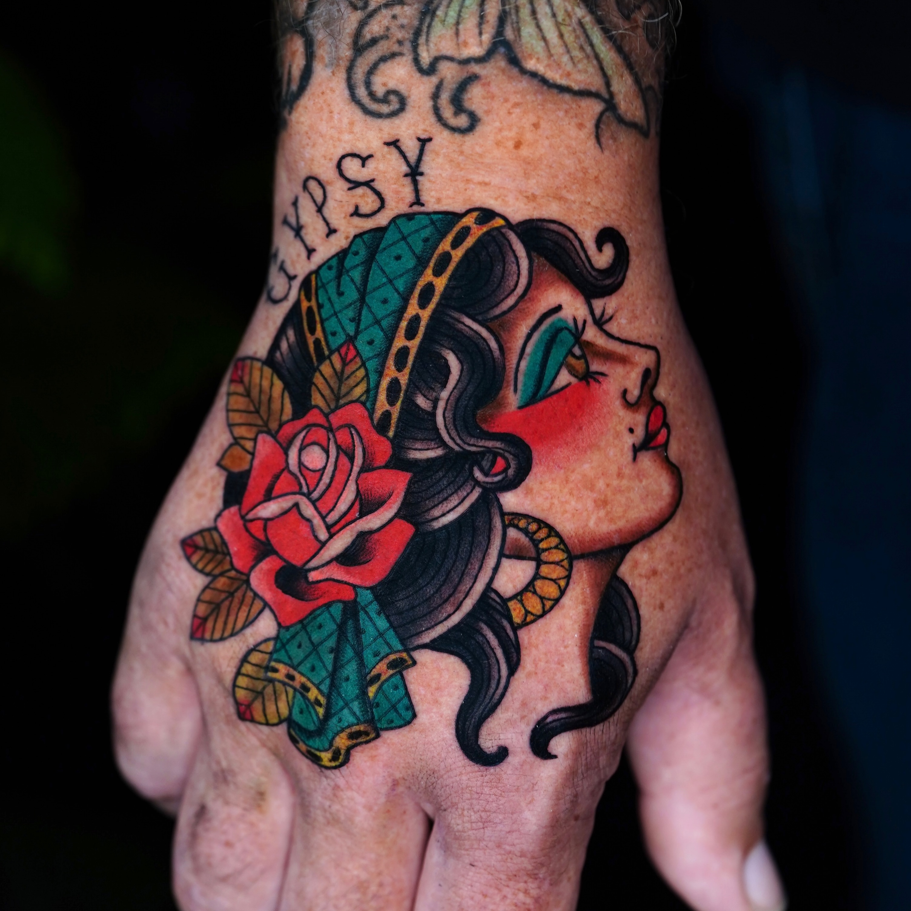 Woman with rose American traditional tattoo on the hand by Mitch Bonifay