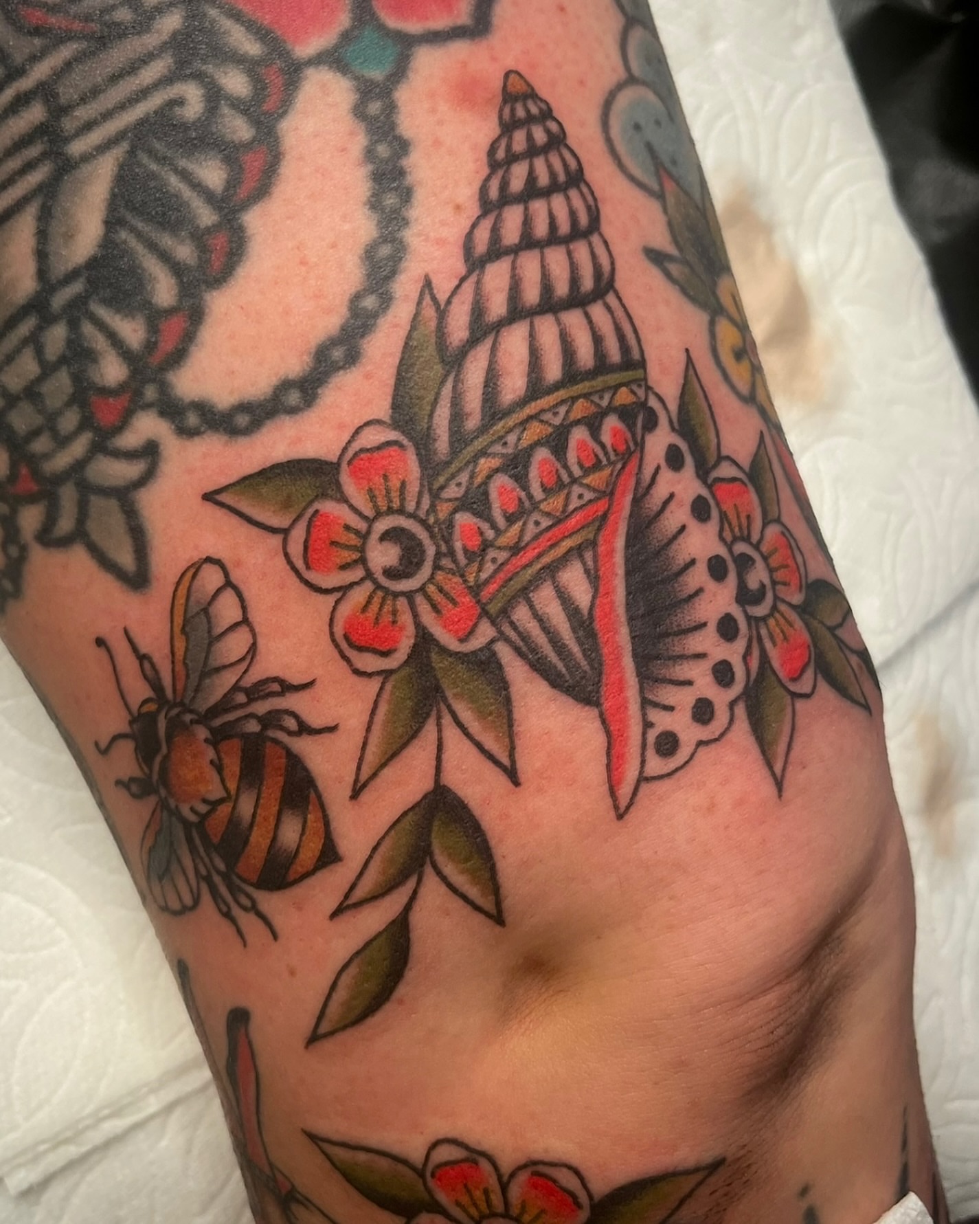 Shell and flowers American traditional tattoo on the forearm by Tiffani Thompson, San Diego, California