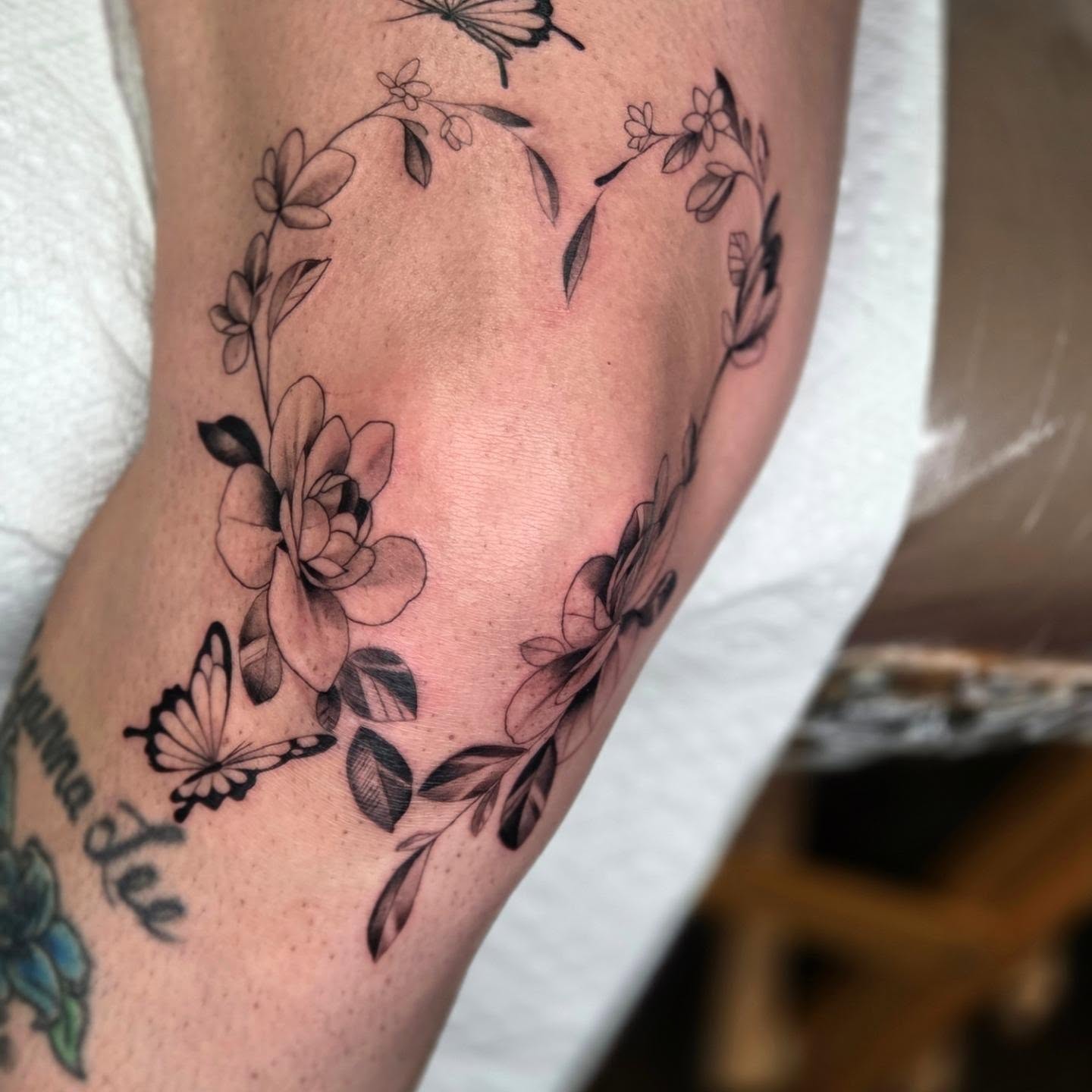 Flower wreath black and grey tattoo on the thigh by Yvette Cebreros