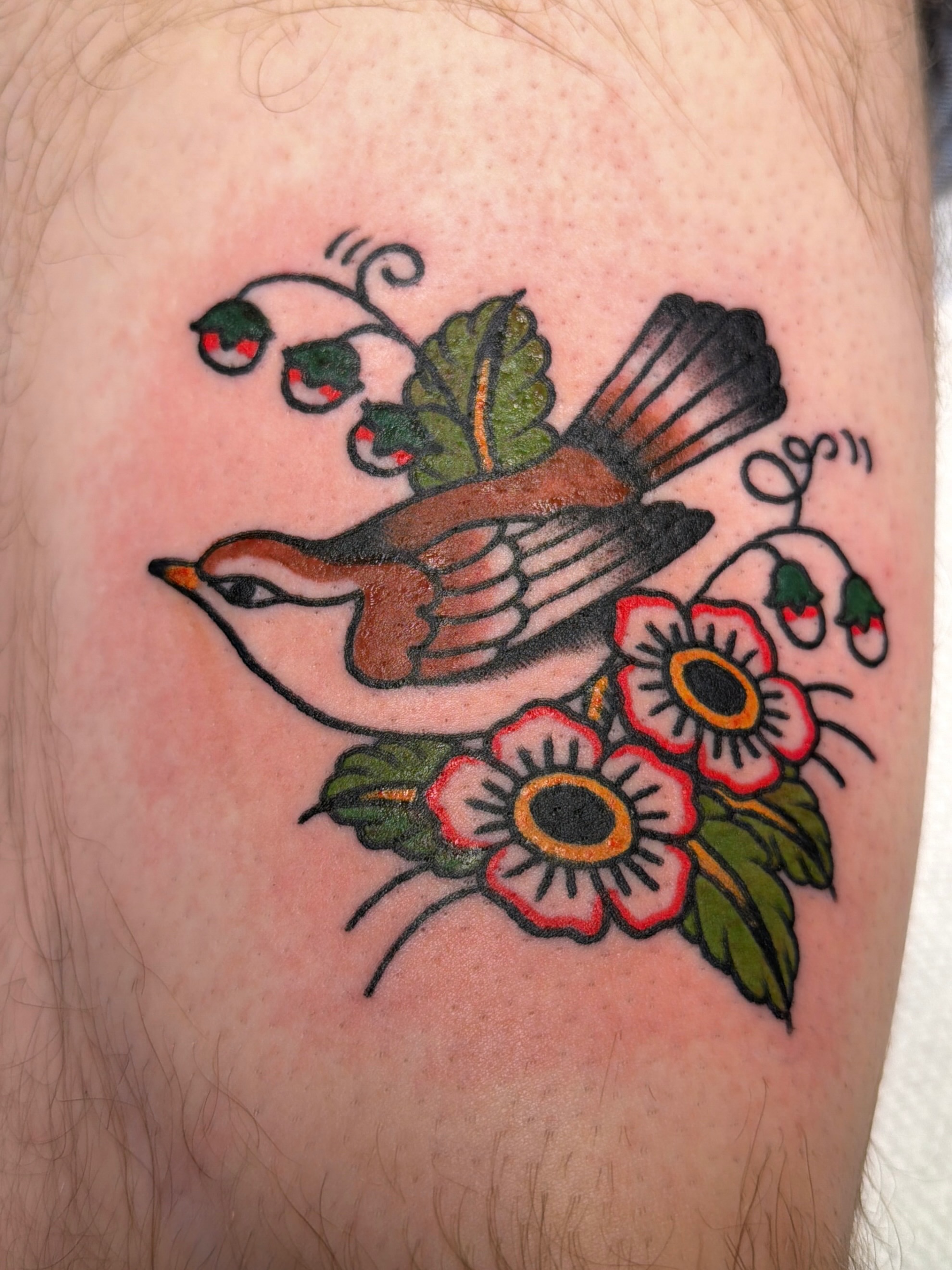 Bird and flowers American traditional tattoo on the thigh by Emma Fox Tattoo