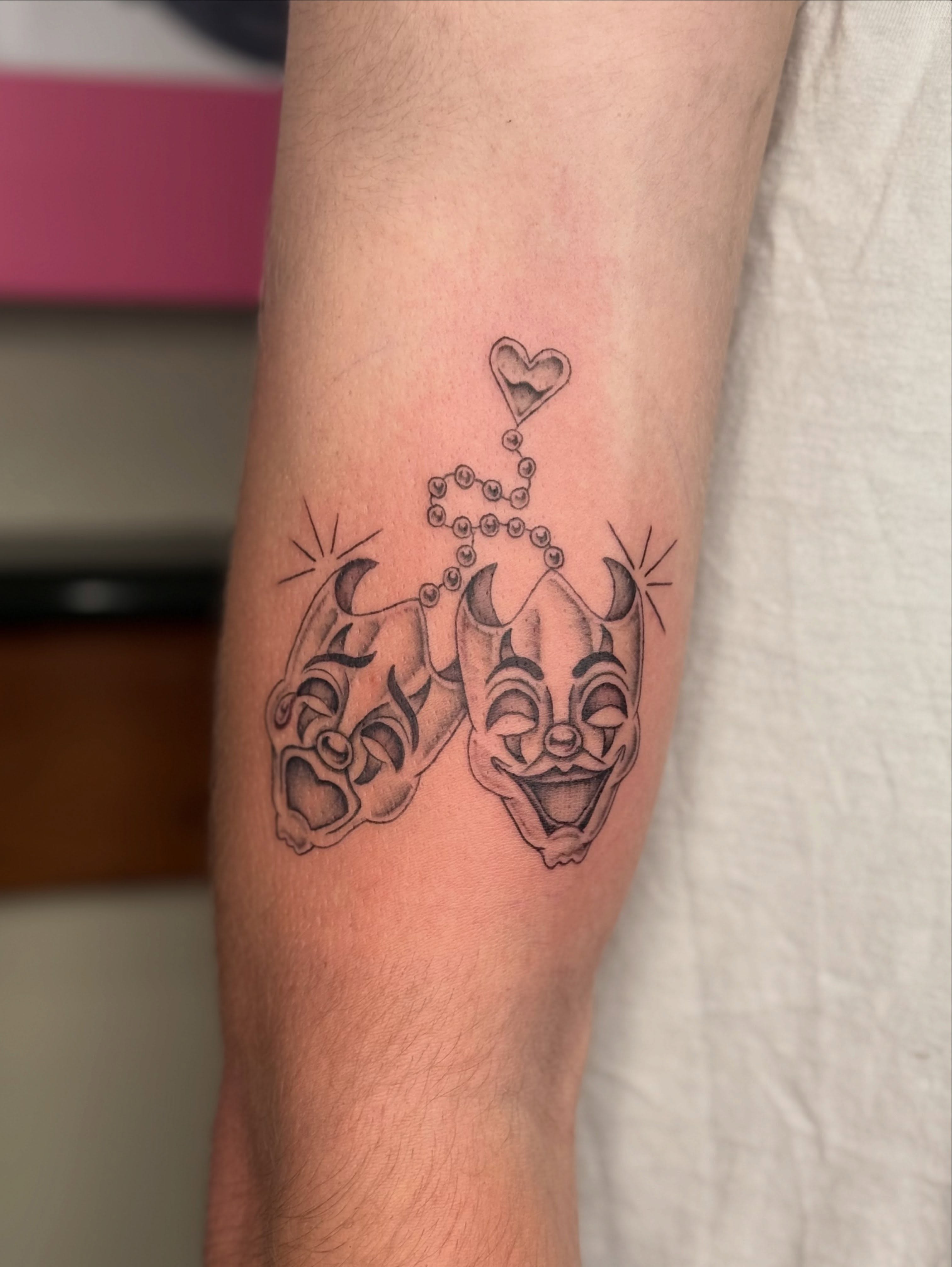 Clown masks black and grey tattoo on the forearm by Taylor Alicia