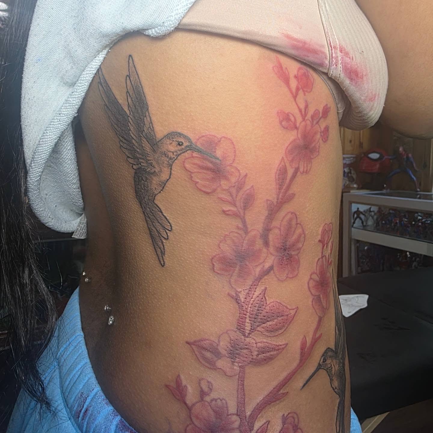 Hummingbird and blossoms realism tattoo on the ribs by Rusty Williams