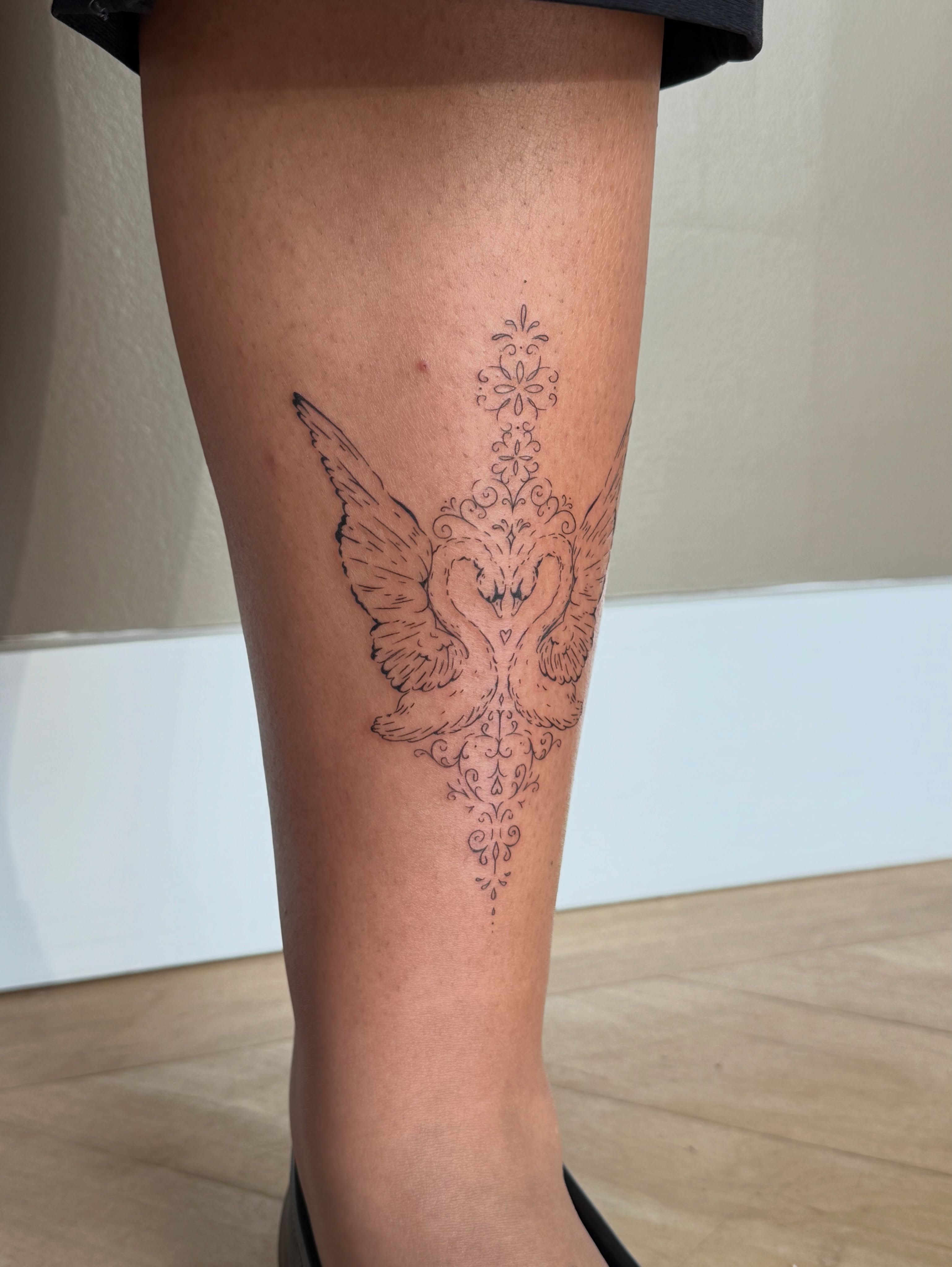 Swans ornamental tattoo on the calf by Fine Line Tattoos