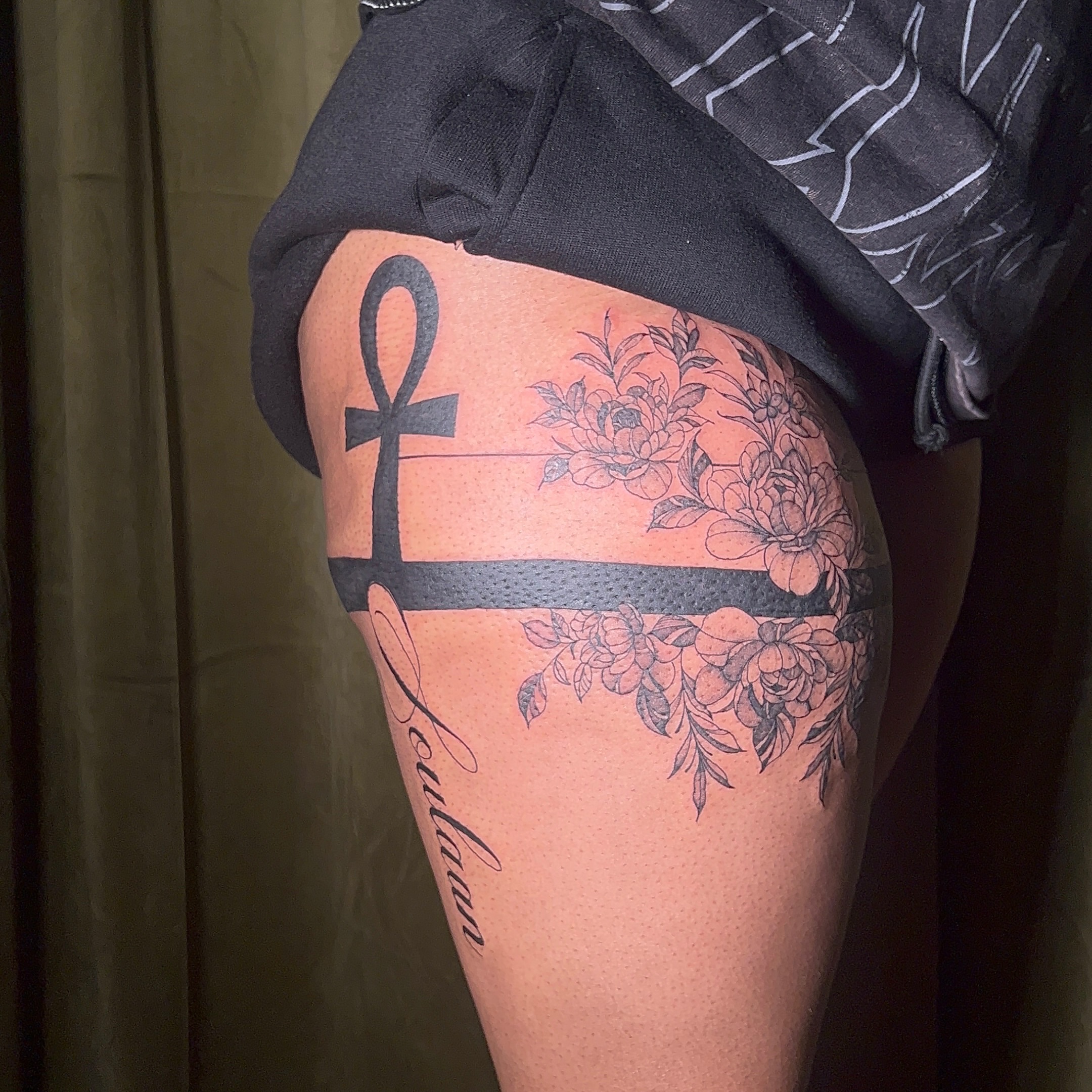 Ankh and floral black and grey tattoo on the thigh by V