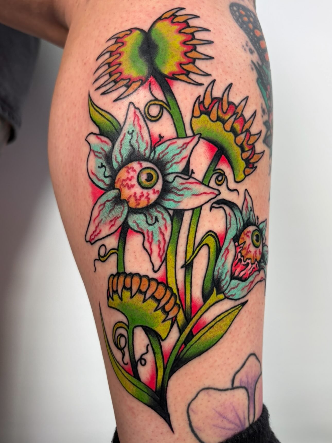 Flower with eyes American traditional tattoo on the thigh by Lorelei