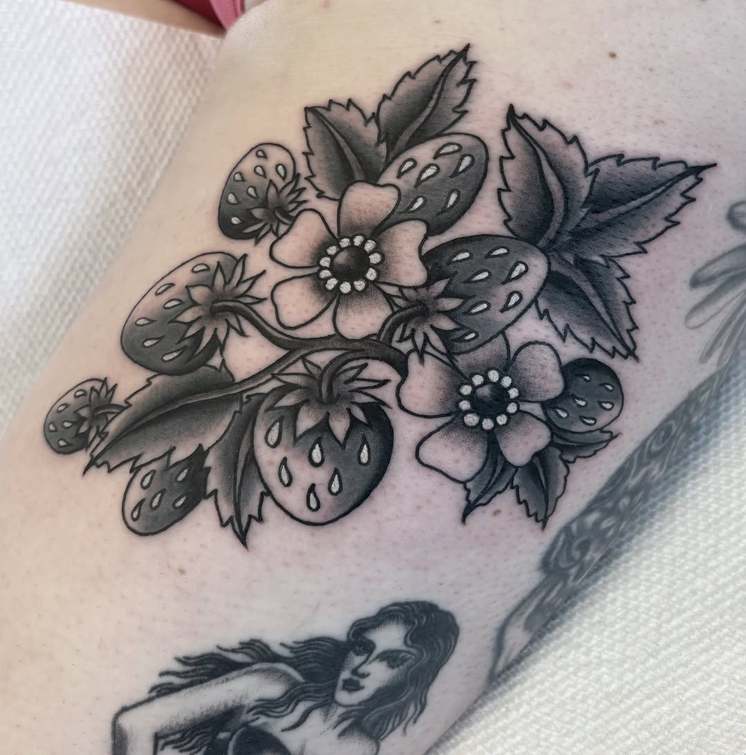 Strawberry and flowers black and grey tattoo on the forearm by Caeli Martin