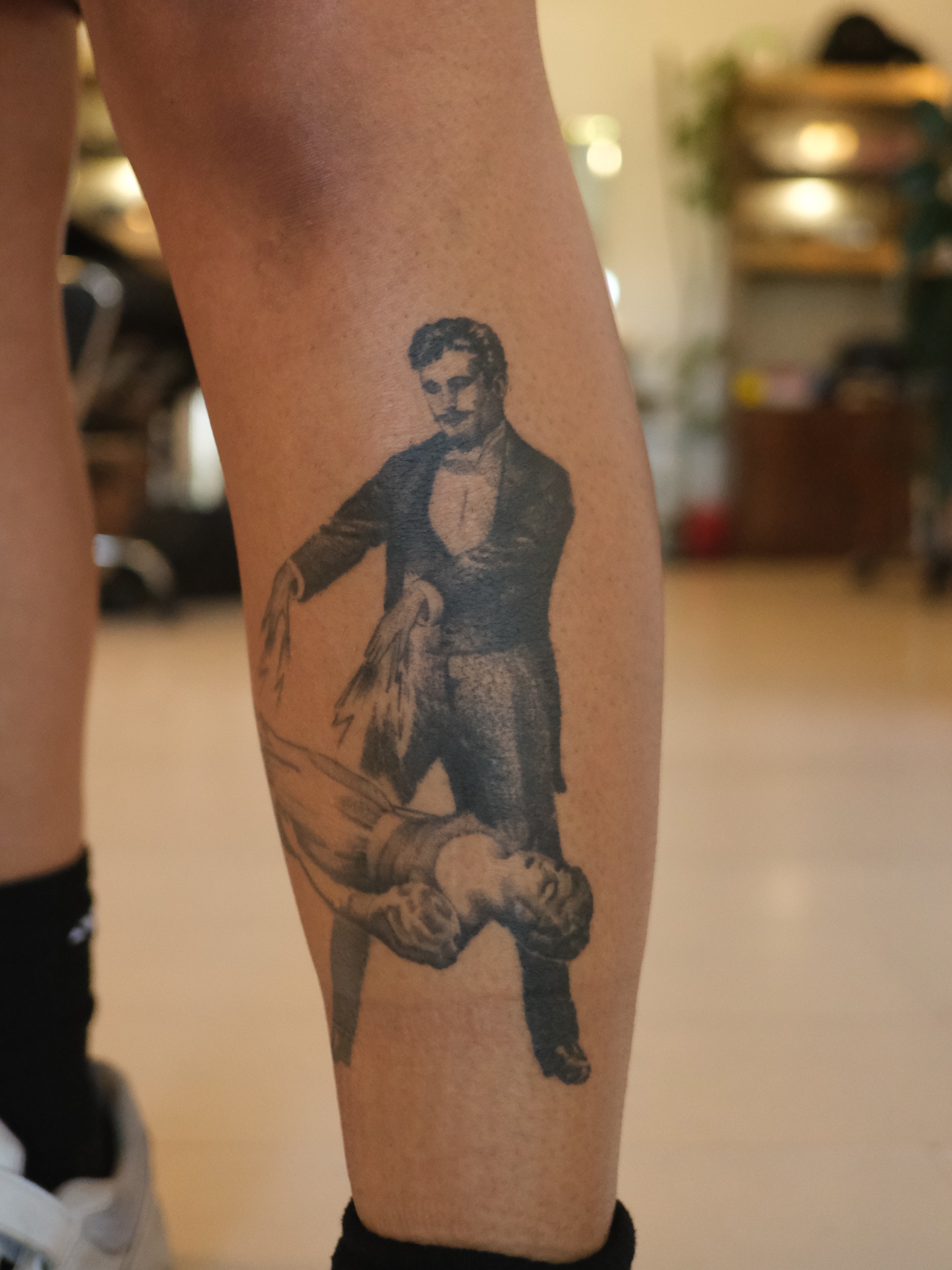 Man carrying woman black and grey tattoo on the calf by Zanereti